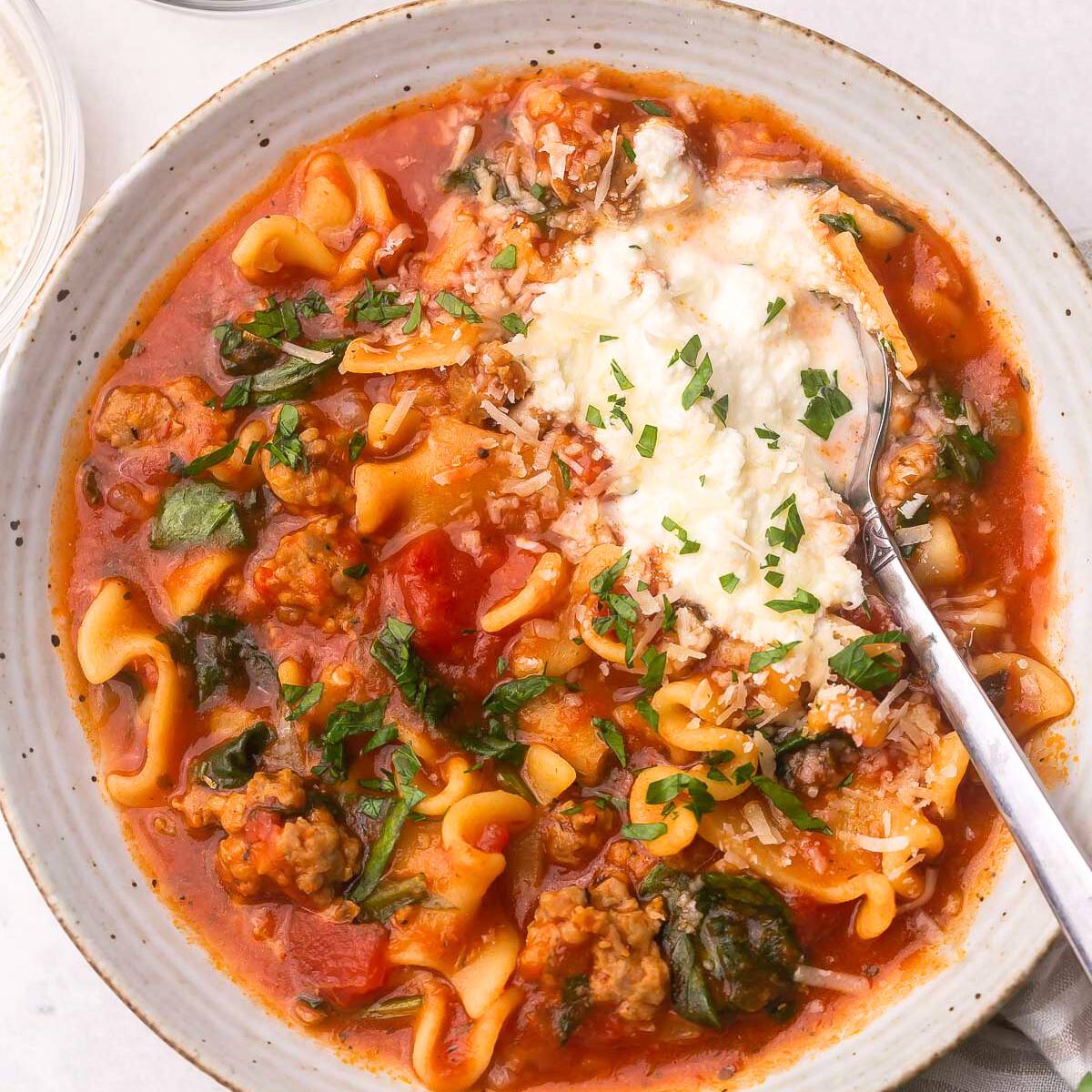 A bowl of hearty lasagna soup with sausage, spinach, and ricotta cheese.