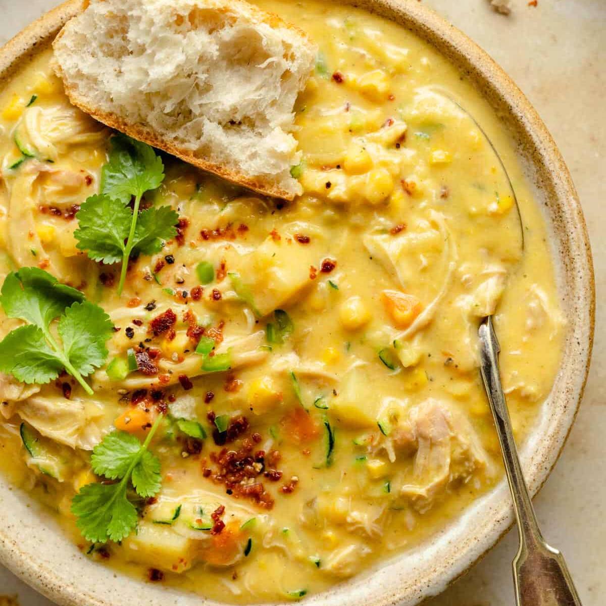 A bowl of creamy corn chowder with chicken, potatoes, and zucchini.