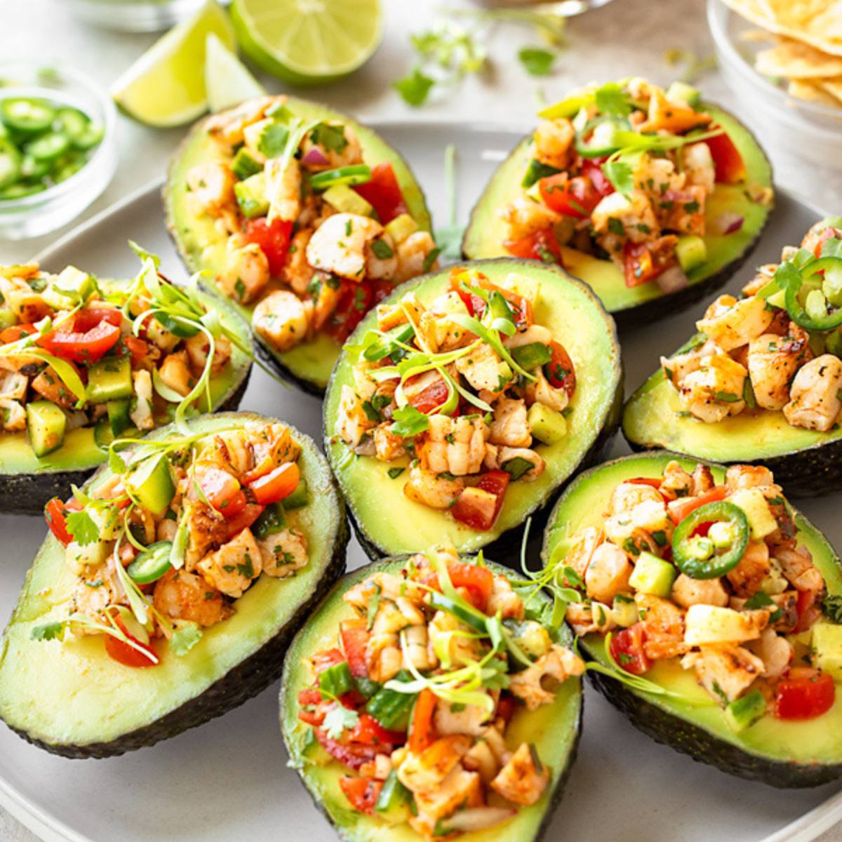 A platter of halved avocados filled with a colorful shrimp ceviche, garnished with cilantro.