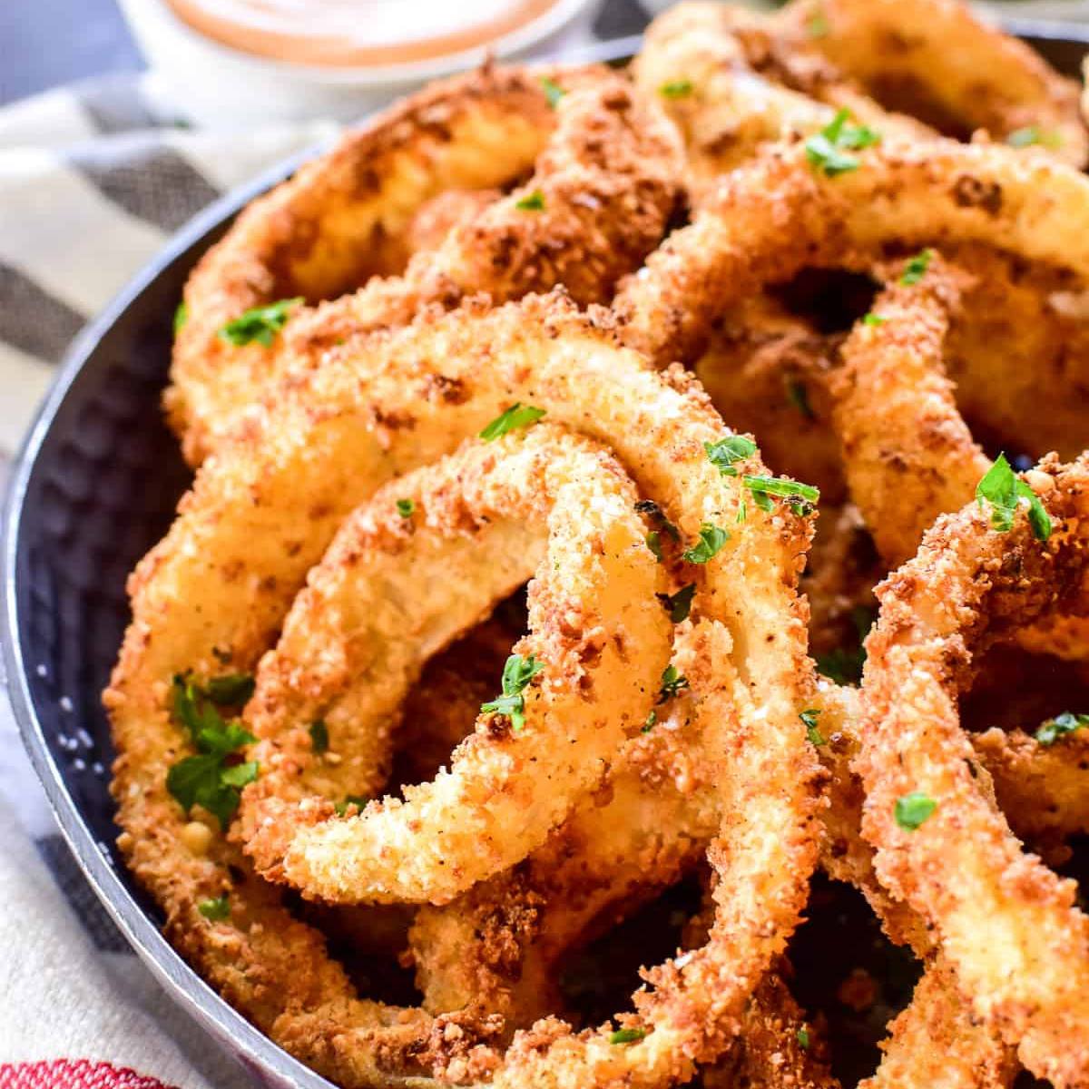 A close-up of a plate of crispy, golden-brown onion rings.