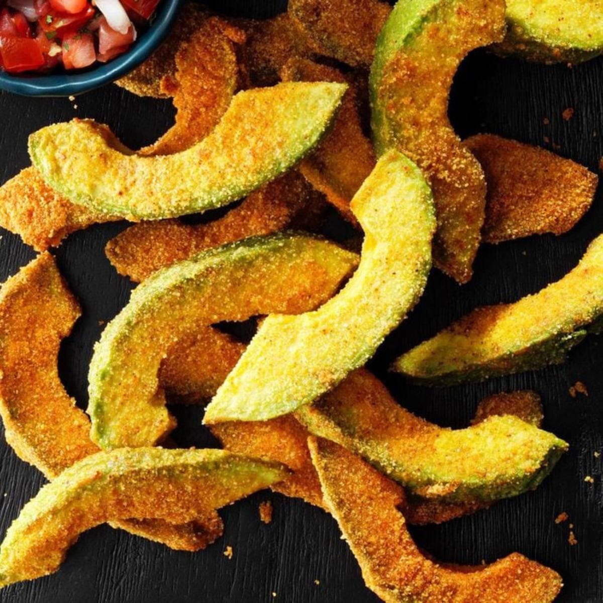 A close-up of a pile of crispy, golden-brown fried avocado slices.