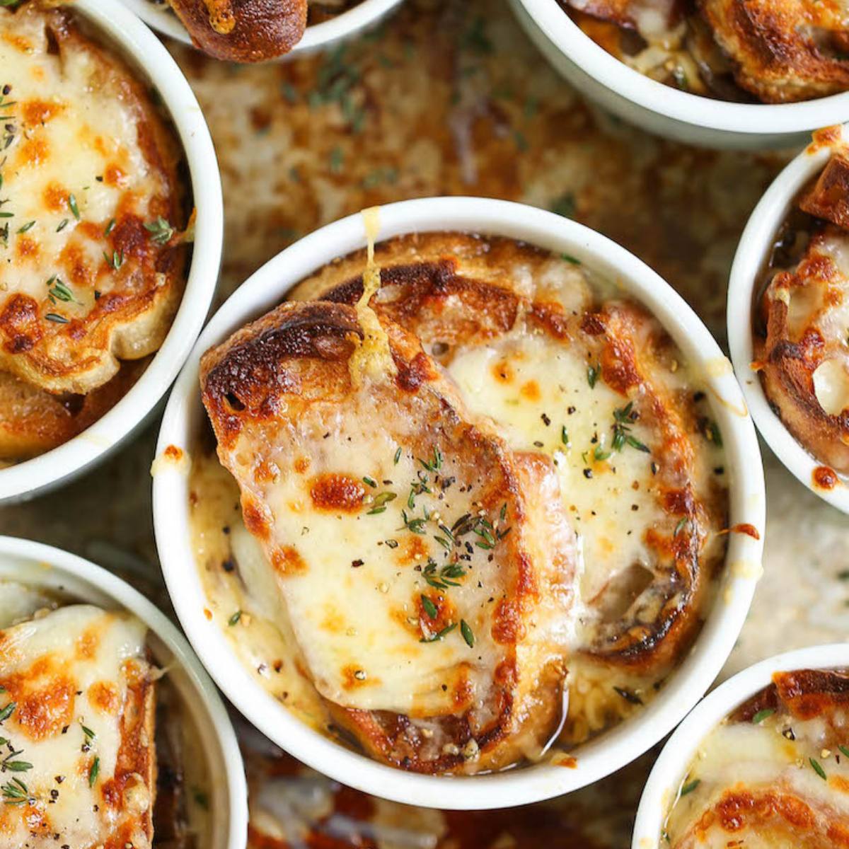 A close-up of bowls of French onion soup with melted cheese and croutons. 