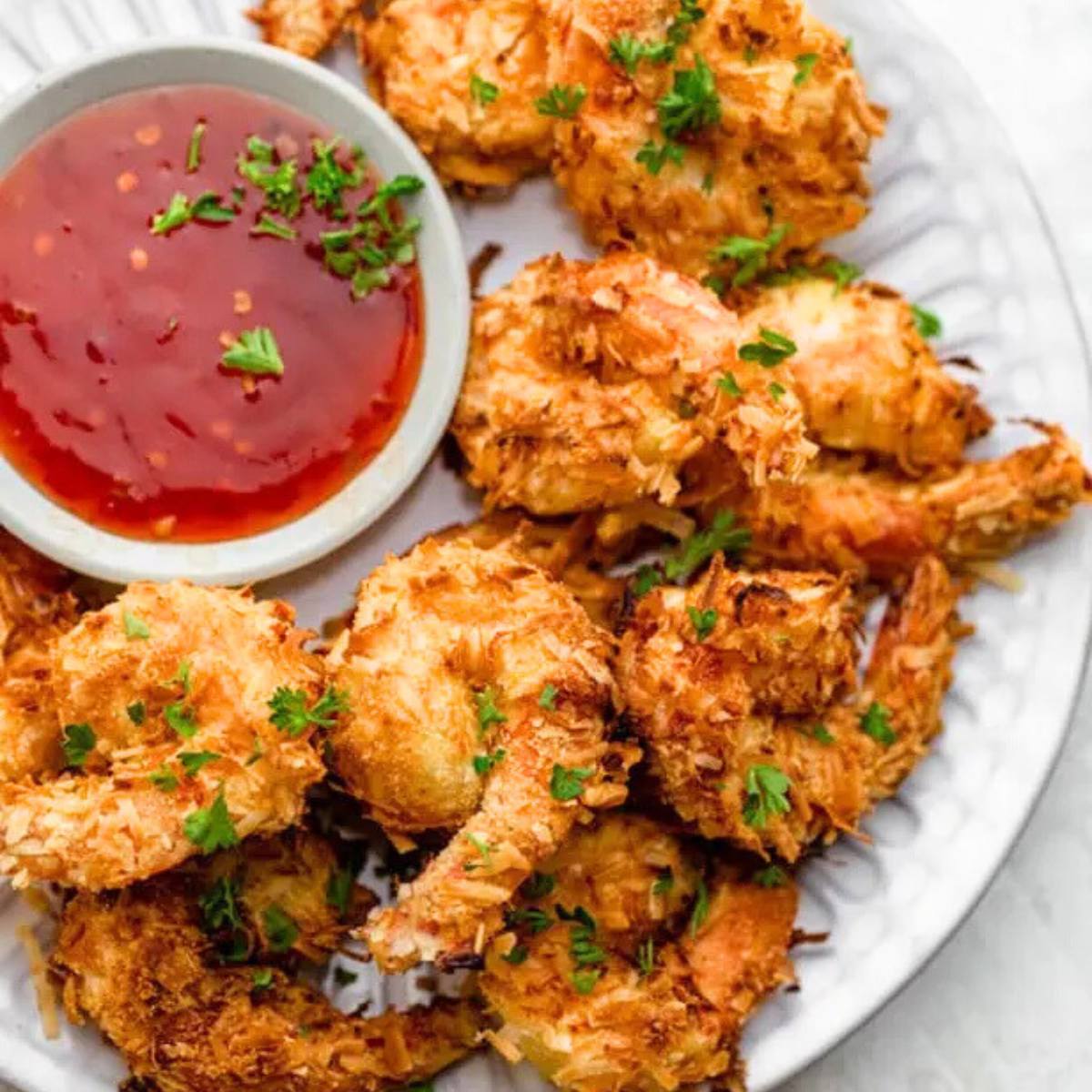 A plate of crispy coconut shrimp with a side of sweet chili sauce.