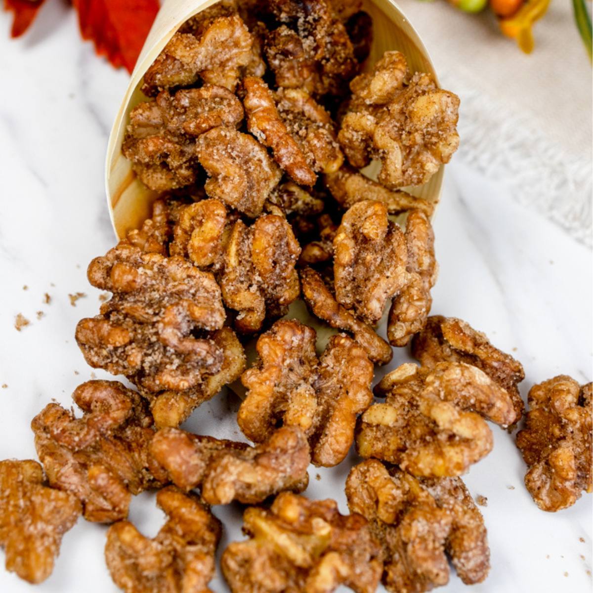 A pile of candied walnuts spilling out of a wooden bowl.