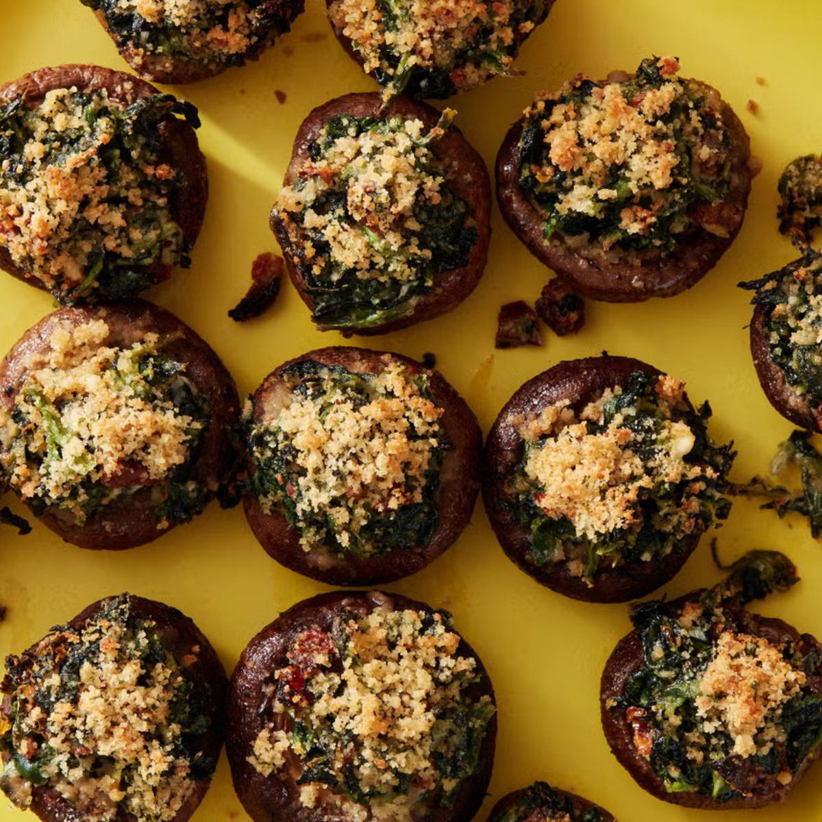 A close-up view of a plate of stuffed mushrooms. The mushrooms are filled with a mixture of spinach and topped with breadcrumbs.