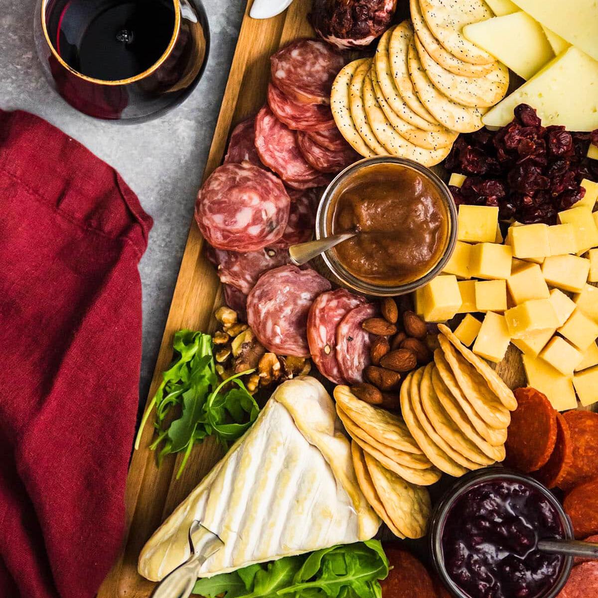 A charcuterie board with a variety of cheeses, meats, crackers, nuts, fruits, and dips.