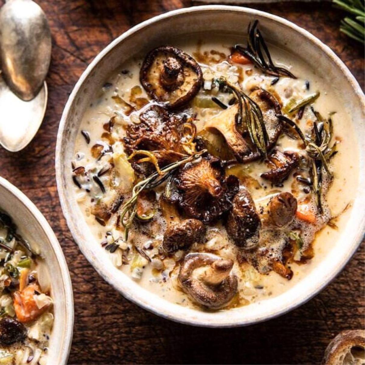 A bowl of creamy mushroom and wild rice soup with roasted mushrooms and rosemary.