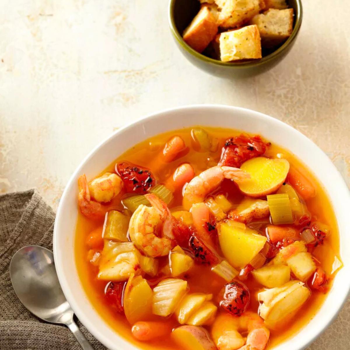 A bowl of hearty seafood chowder with shrimp, potatoes, and vegetables. 