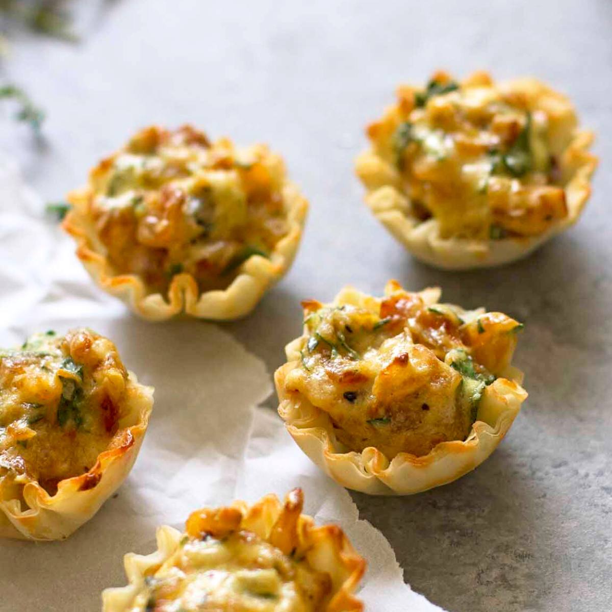 Four golden-brown mini quiches with flaky pastry crusts, filled with a creamy egg and cheese mixture.