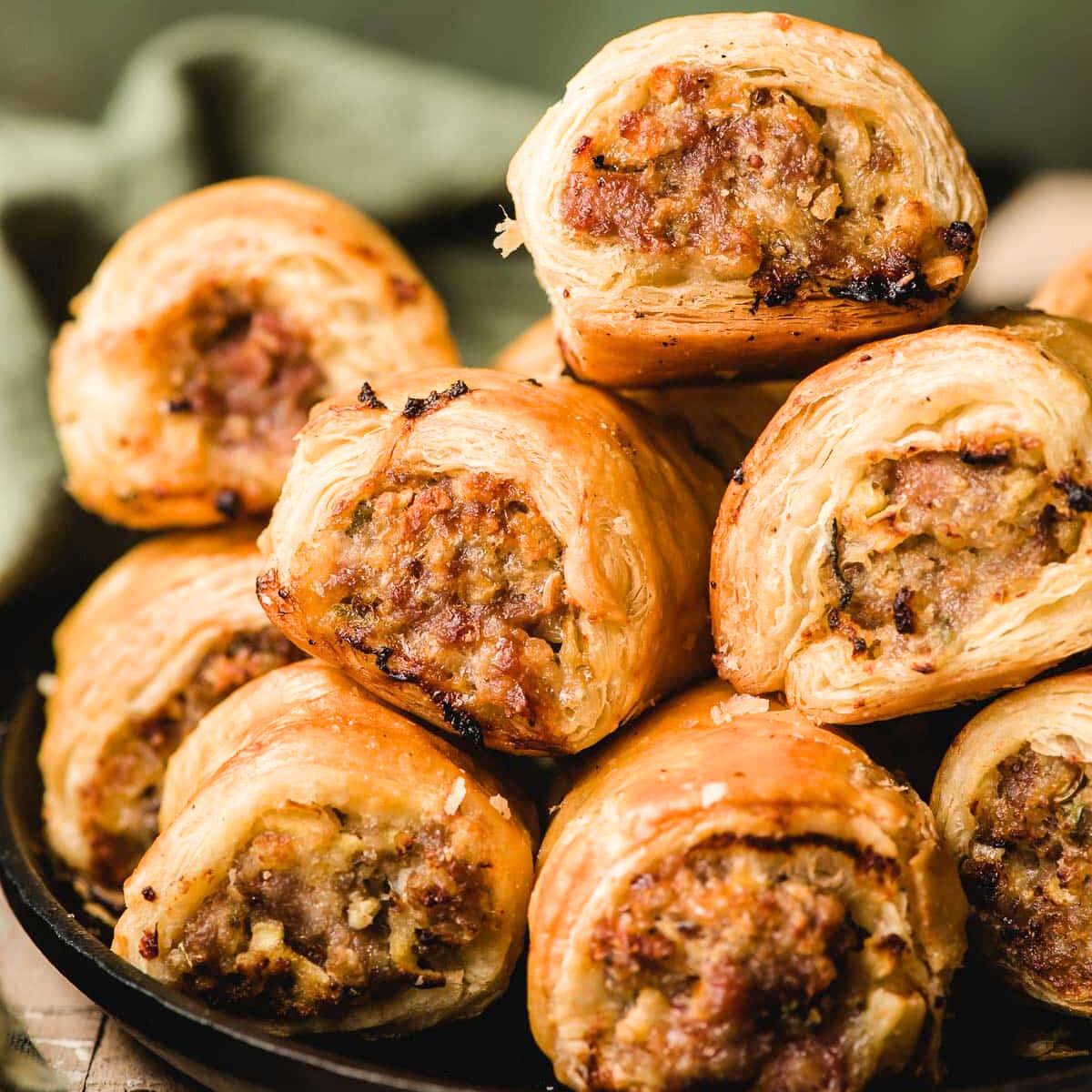 A close-up of a stack of golden-brown sausage rolls.