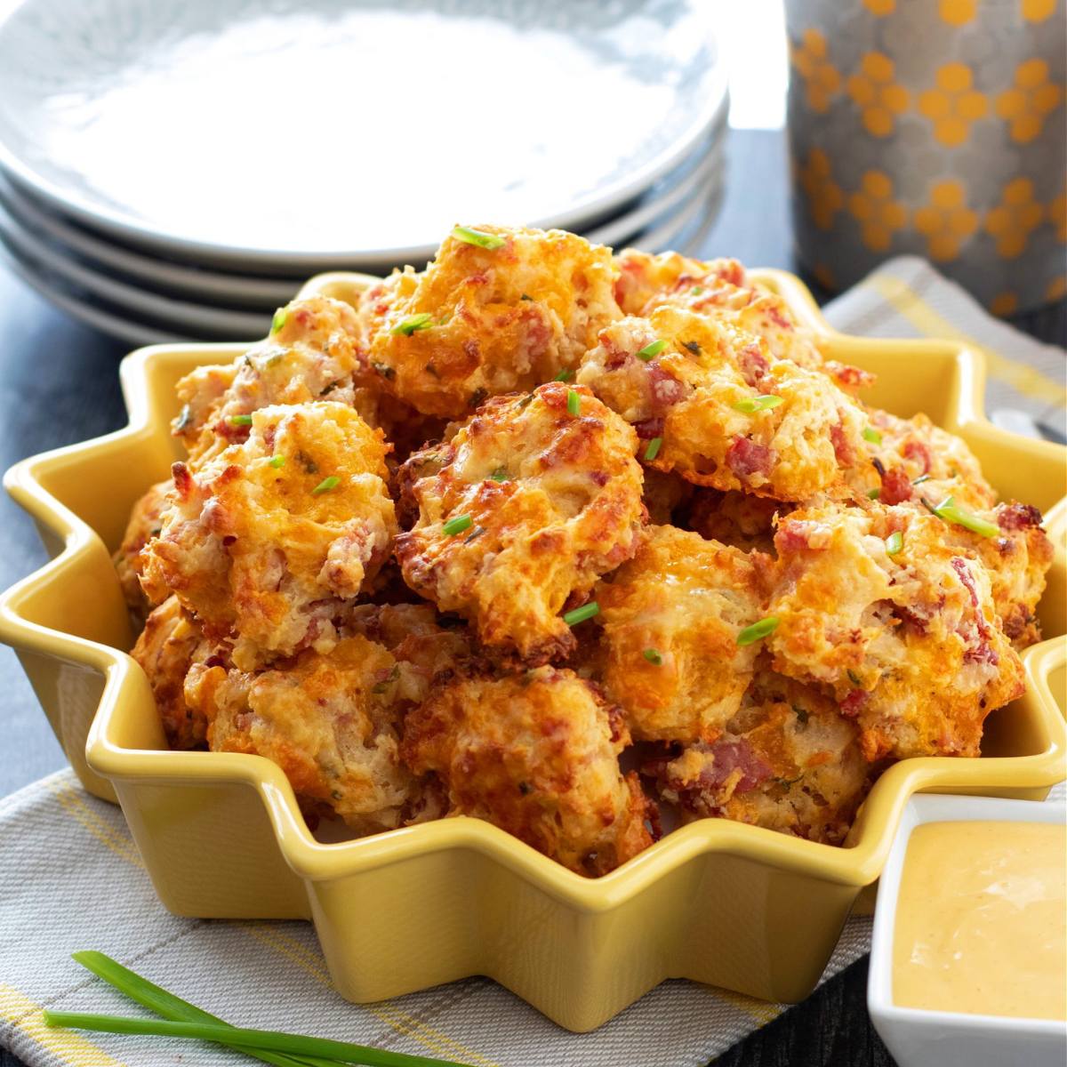 A bowl of golden-brown cheesy bites, garnished with chives.