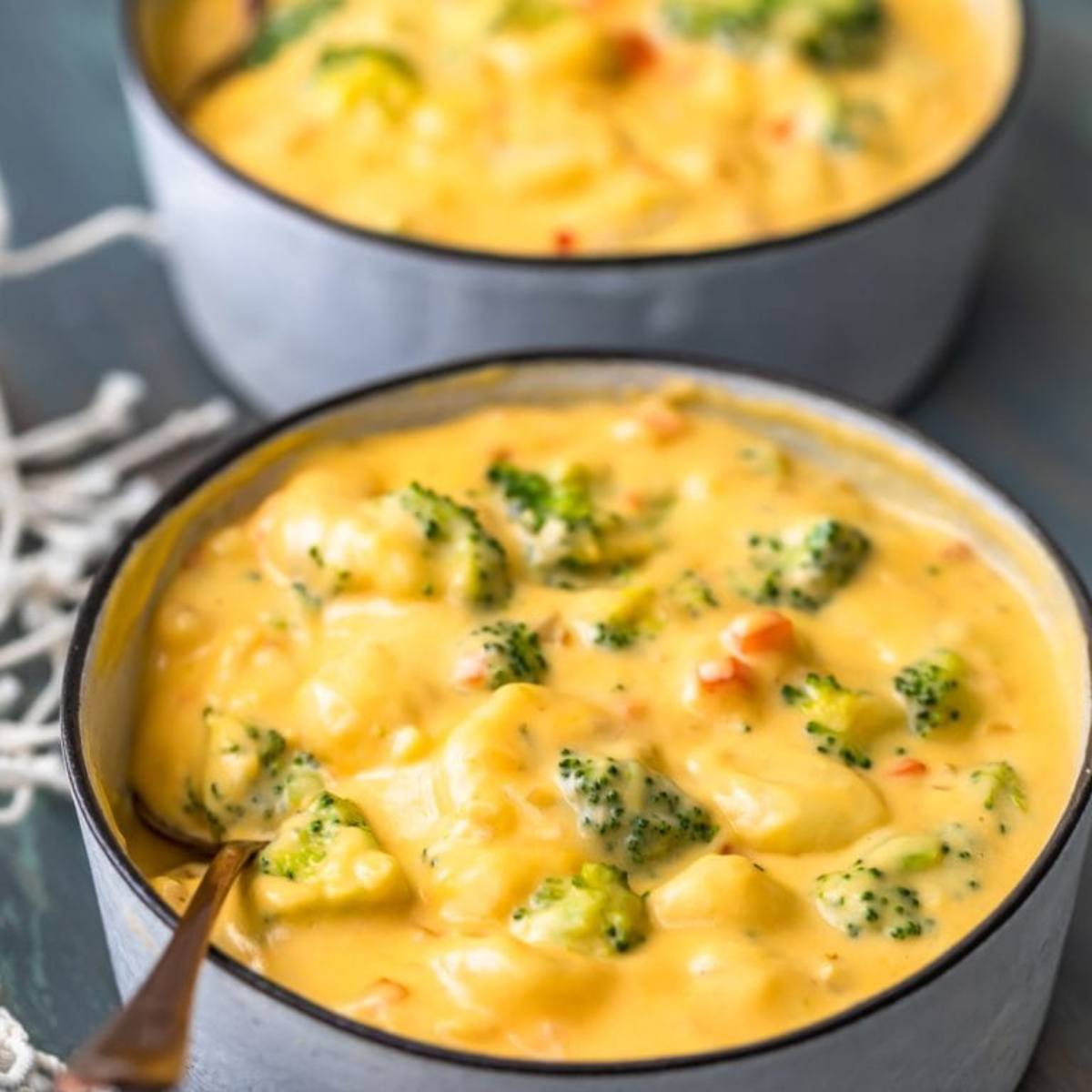 Two bowls of creamy broccoli cheddar soup with gnocchi. 