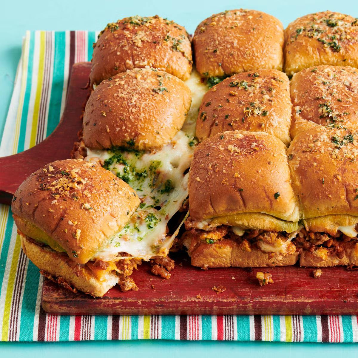 A large pan of cheesy, meaty sliders with melted cheese oozing out.