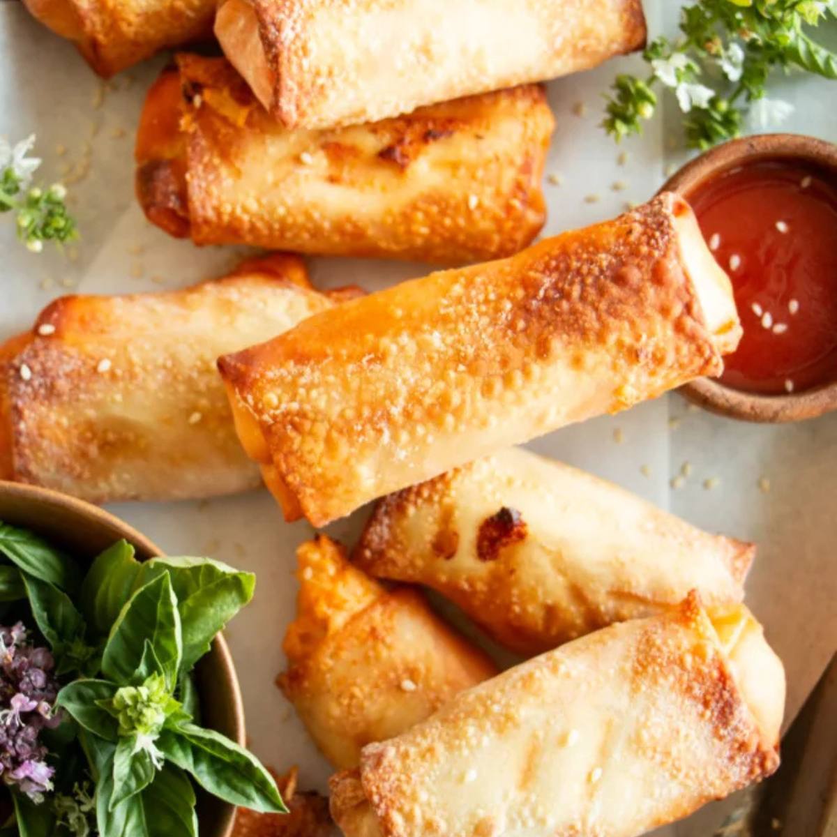 A plate of crispy, golden-brown egg rolls with a side of dipping sauce.