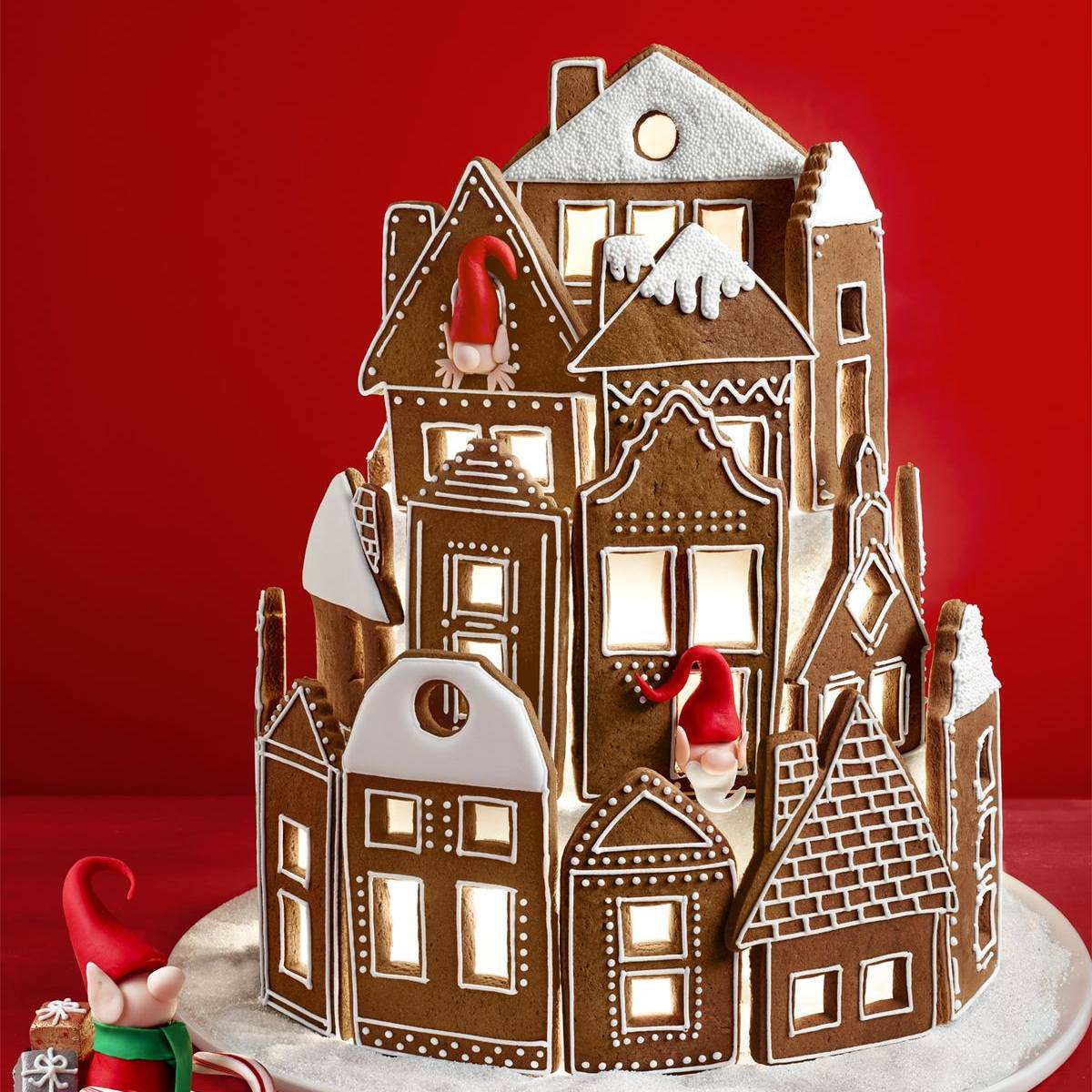 A whimsical gingerbread village with multiple houses lit up from within, featuring adorable gingerbread gnomes.