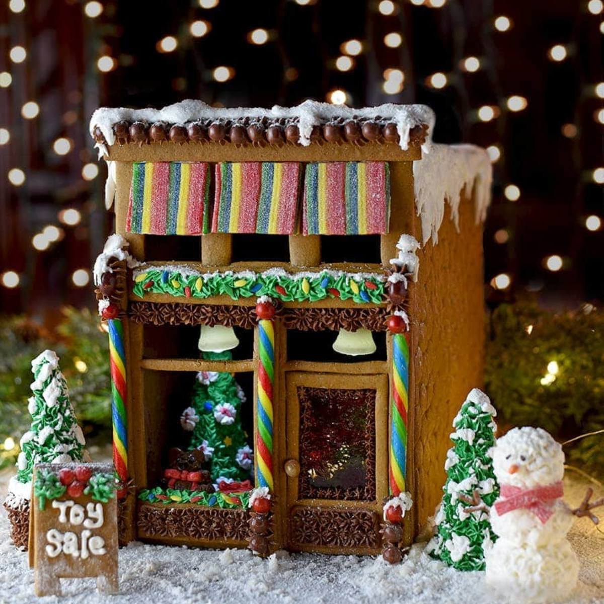 An elaborately decorated gingerbread house resembling a toy store, with candy decorations and a "Toy Sale" sign.