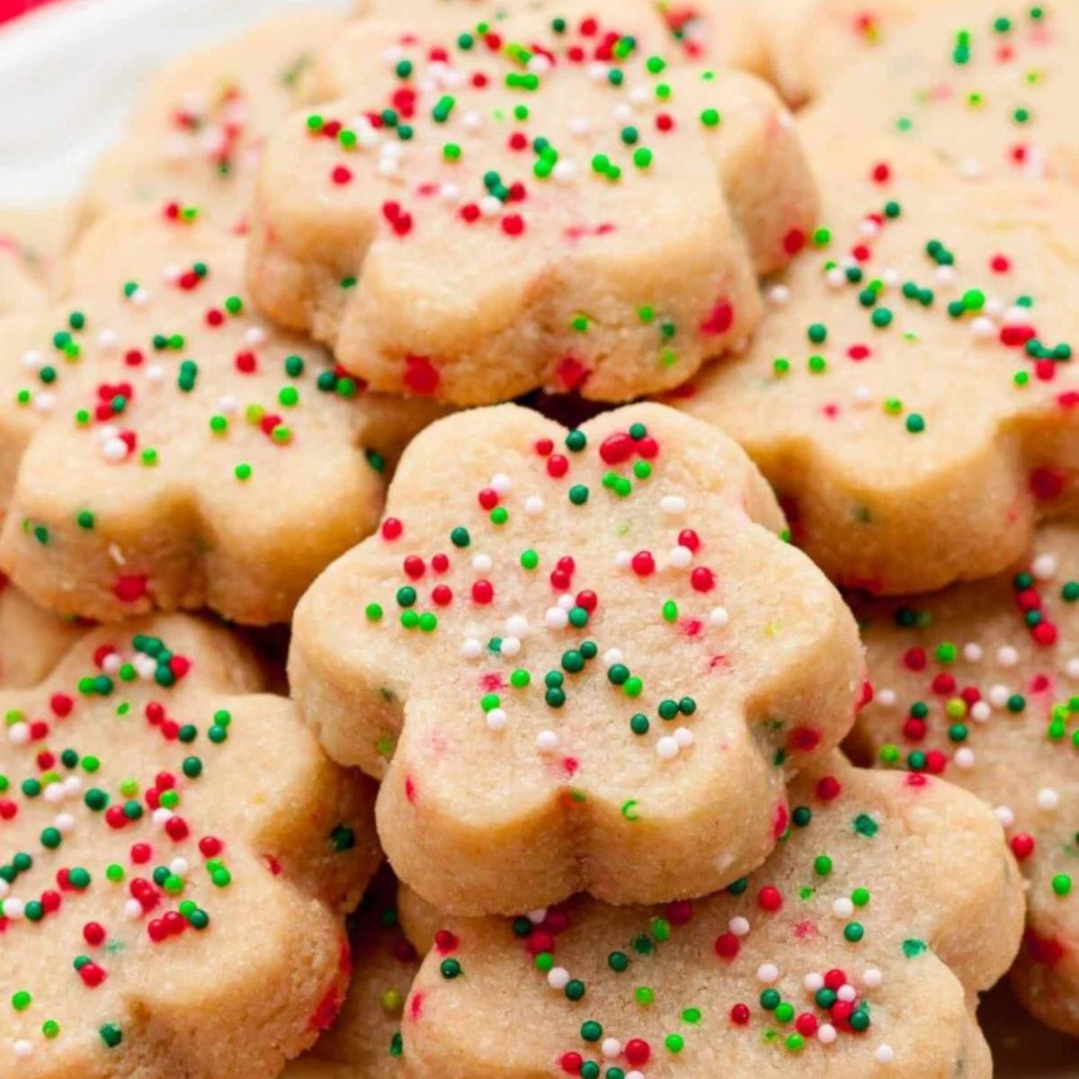 A plate of festive shortbread cookies decorated with colorful sprinkles. The cookies are shaped like stars and have a buttery, crumbly texture.