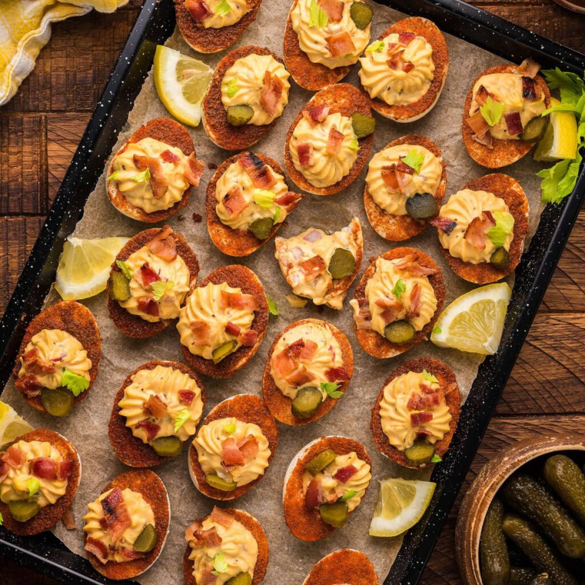 A baking sheet filled with deviled eggs topped with bacon bits, pickled relish, and paprika.