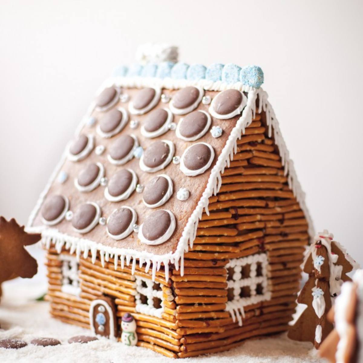 A unique gingerbread house with a roof made of chocolate candies and walls constructed from pretzel sticks.