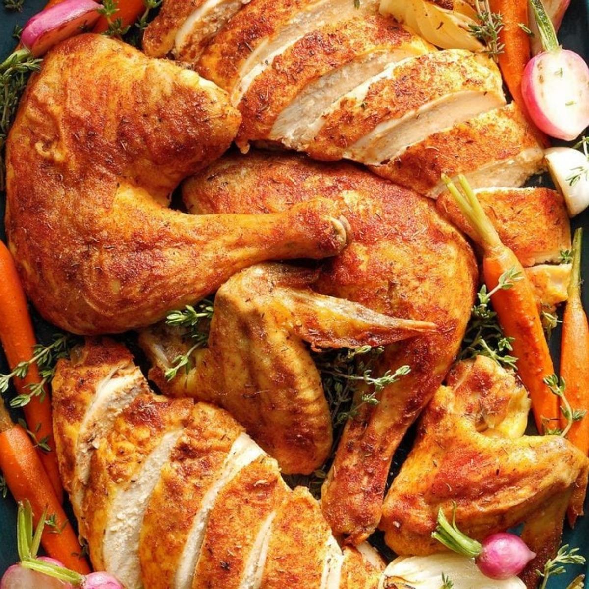 A golden-brown, roasted chicken cut into pieces and arranged on a platter. 