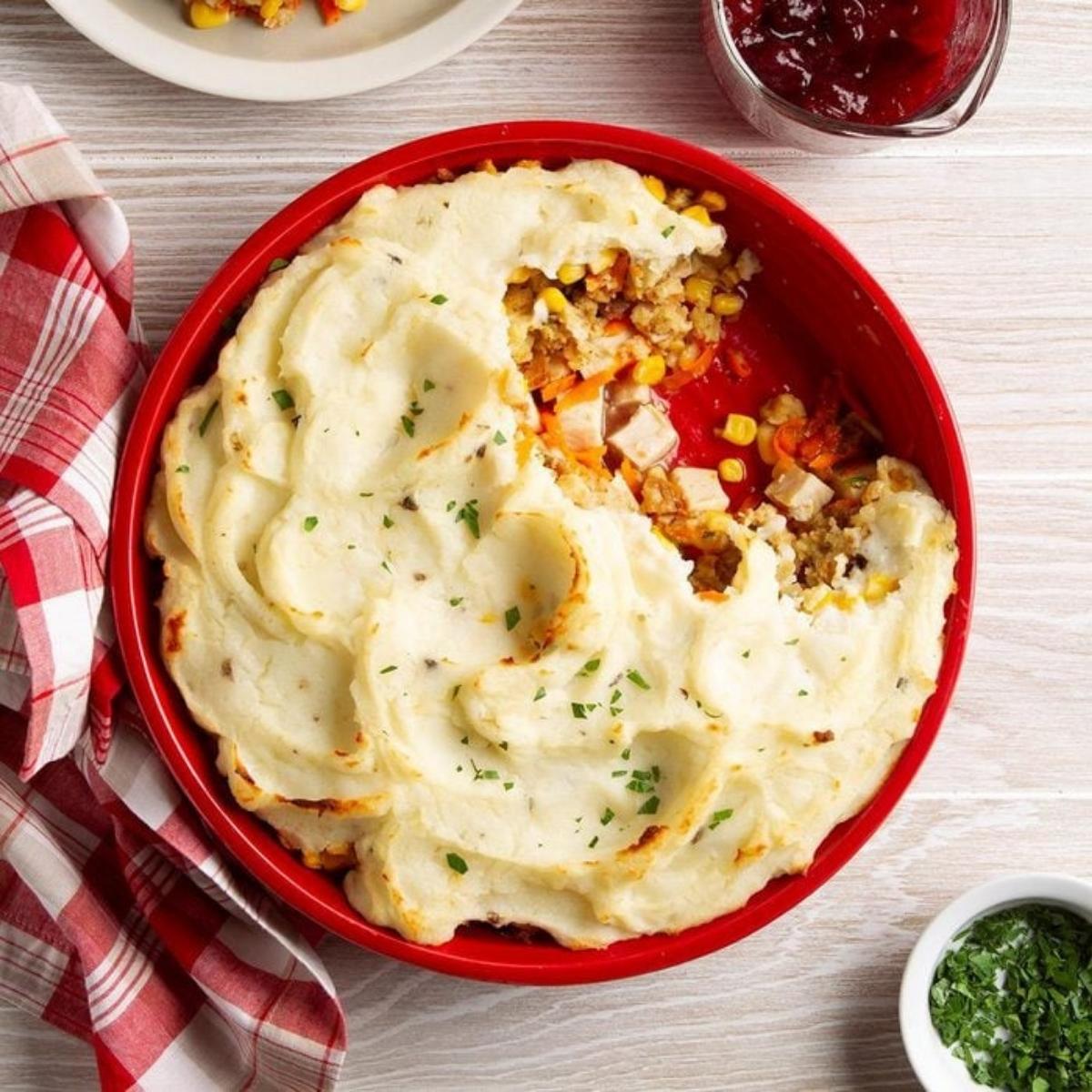 A hearty and comforting shepherd's pie. The pie is topped with a fluffy layer of mashed potatoes and a scoop has been taken out to reveal the savory filling of ground meat, vegetables, and gravy.