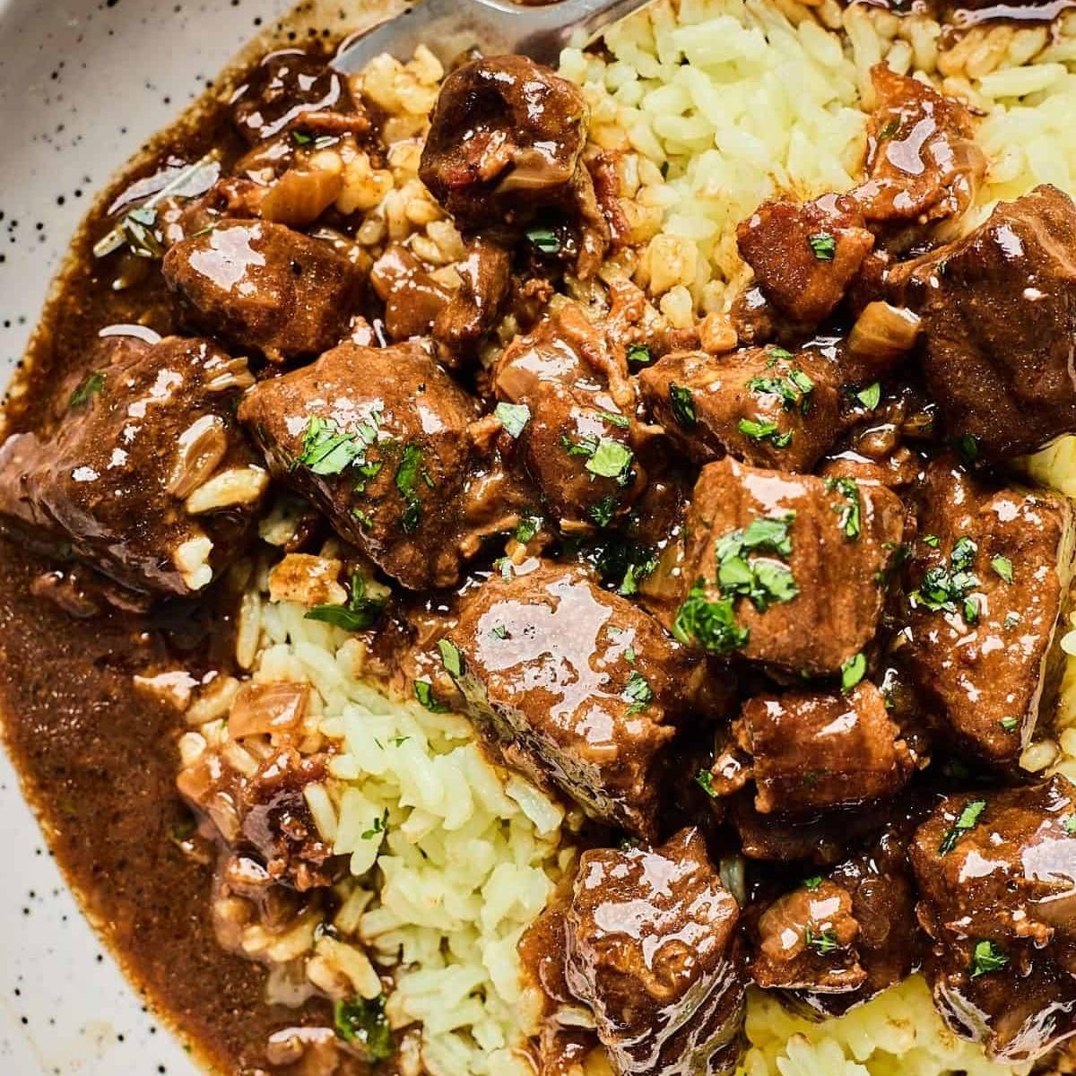 A bowl of hearty beef stew served over egg noodles. The stew is rich and flavorful, with tender chunks of beef in a savory gravy.