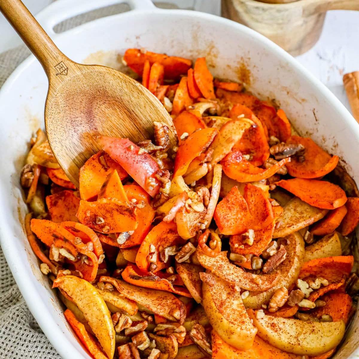 A dish of roasted apple and sweet potato slices topped with pecans and cinnamon.