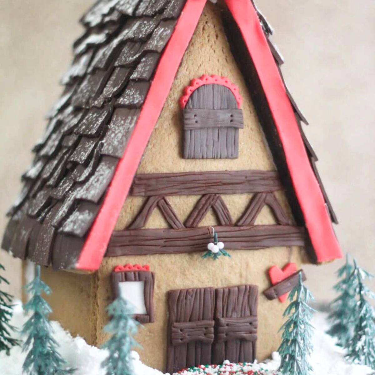 A gingerbread house with a detailed thatched roof, a wooden door, and a snowy landscape.