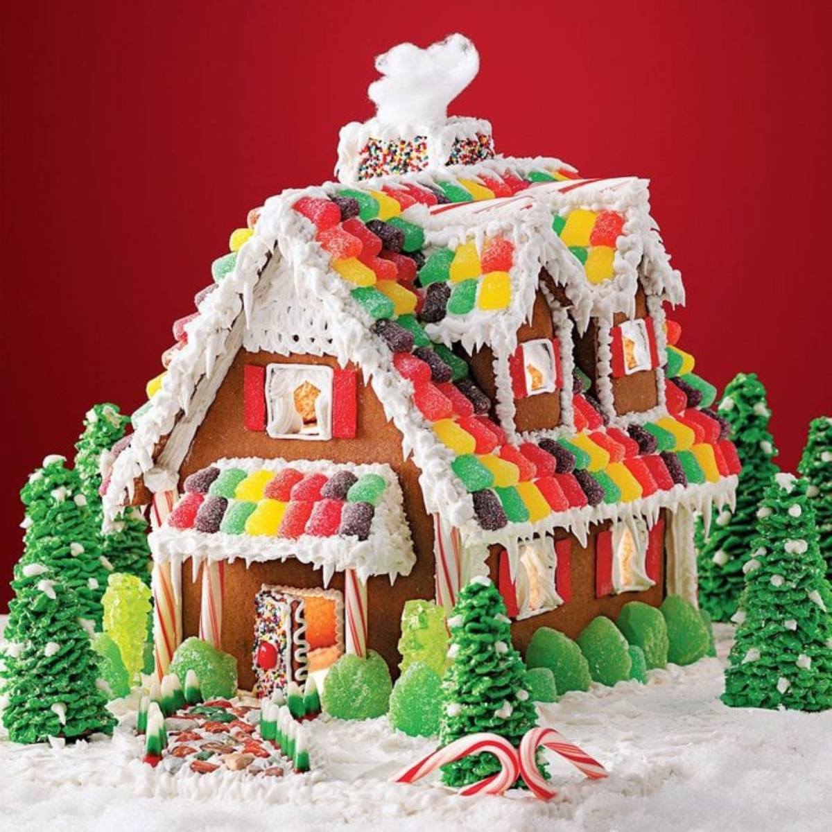 An elaborately decorated gingerbread house with a candy roof, gumdrop trees, and a frosted walkway.