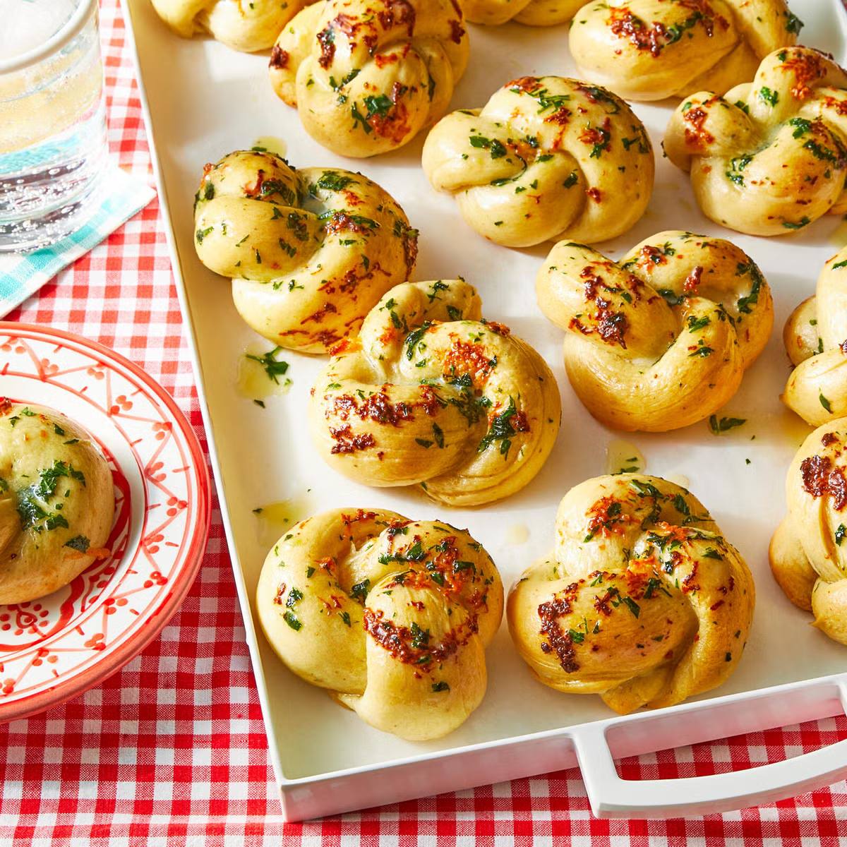 A tray of freshly baked garlic knots, drizzled with garlic butter and sprinkled with herbs.