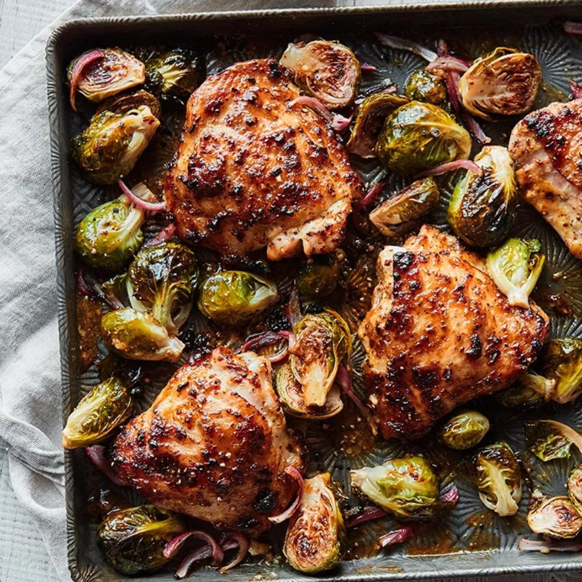 A sheet pan dinner featuring juicy, honey mustard-glazed chicken thighs roasted alongside crisp Brussels sprouts and caramelized red onions.