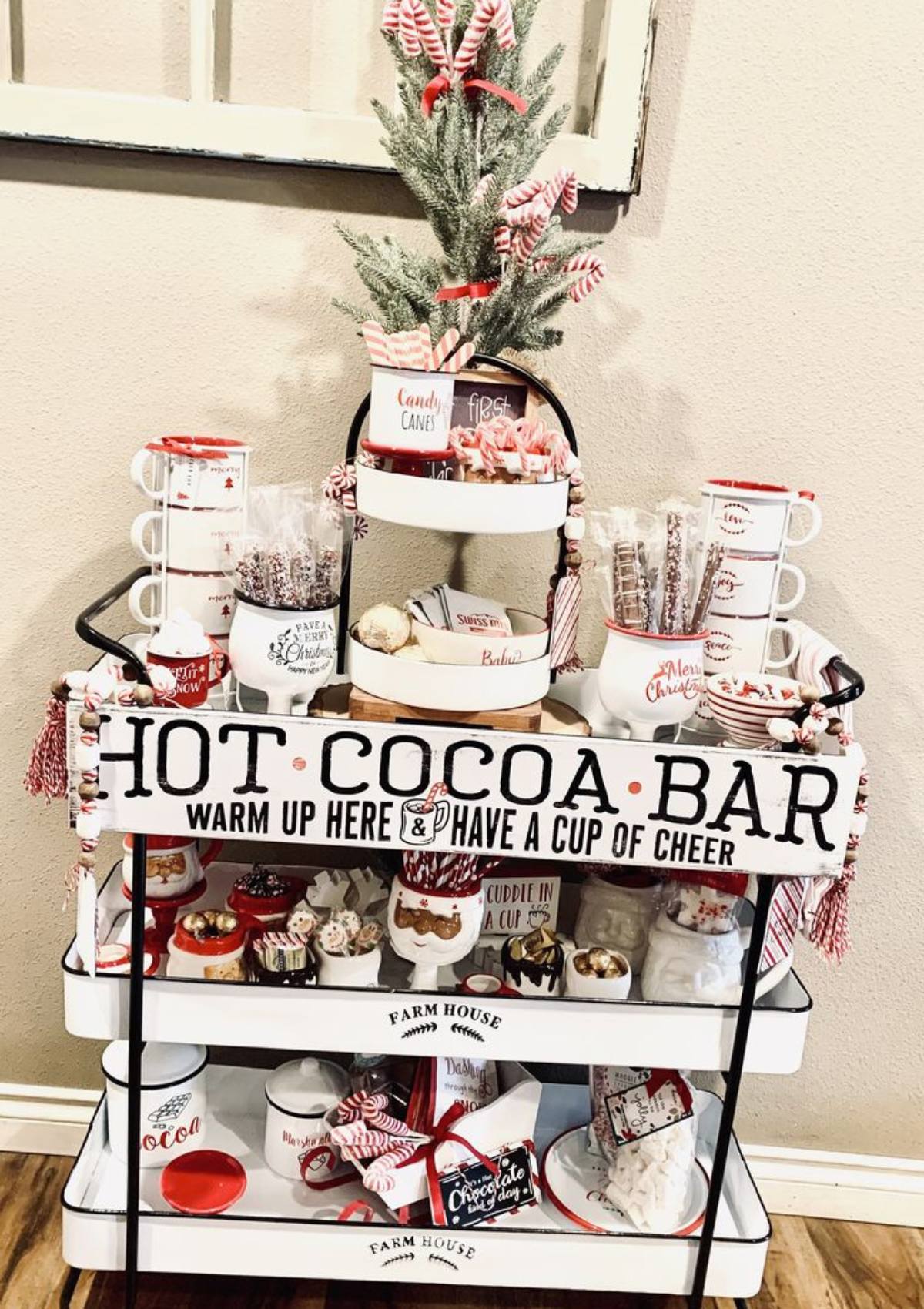 A festive hot cocoa bar on a rolling cart with various ingredients and decorations.