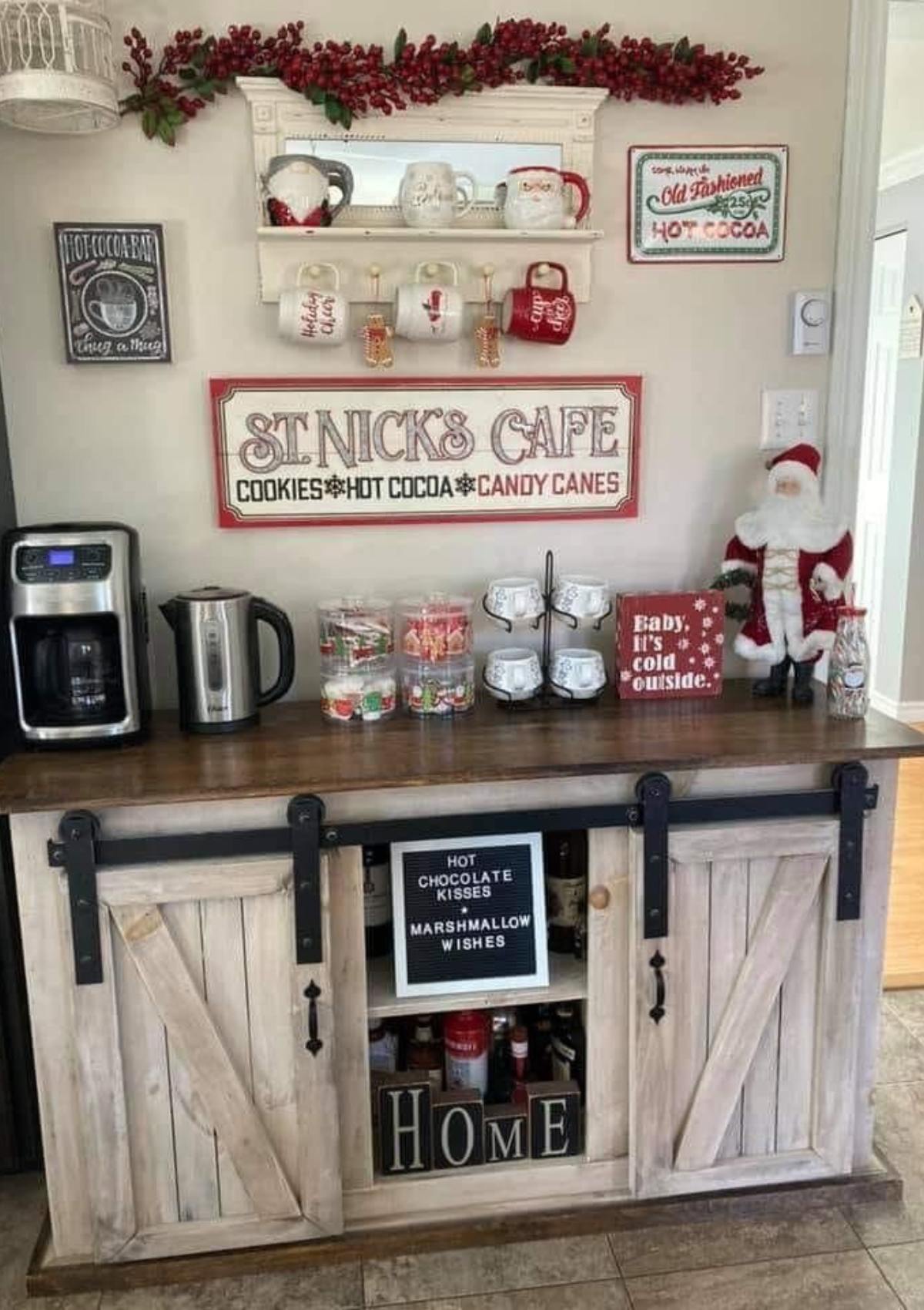 A festive hot cocoa bar setup with a variety of mugs, candy canes, and other decorations. The bar has a sign that says "St. Nick's Cafe: Cookies, Hot Cocoa, Candy Canes".