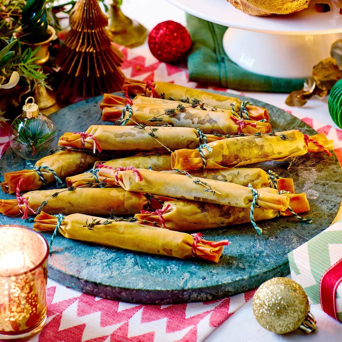 A festive platter of golden-brown parcels filled with a savory stuffing, tied with twine and garnished with fresh thyme sprigs. 