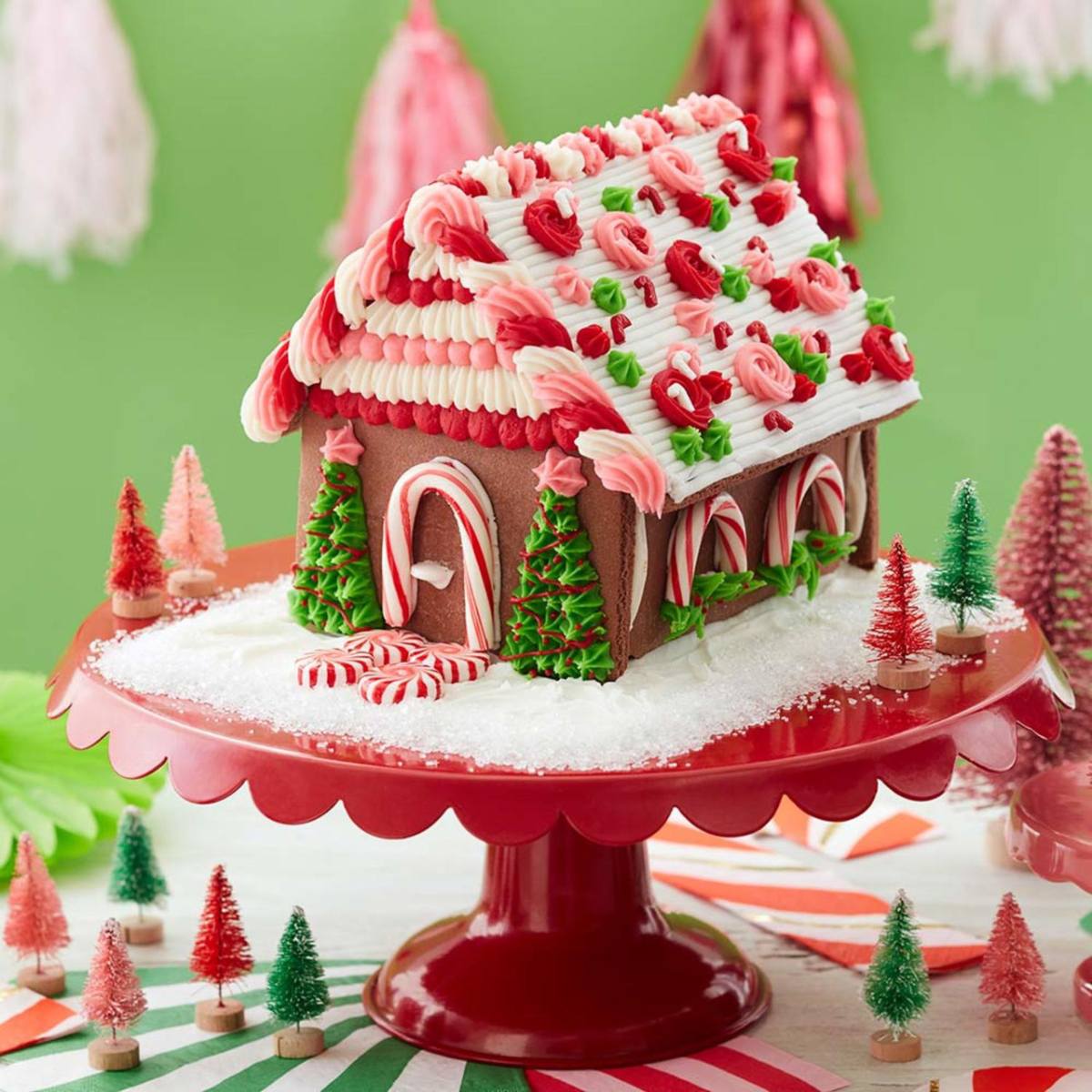 An elaborately decorated gingerbread house with a roof covered in frosting roses and candy canes.