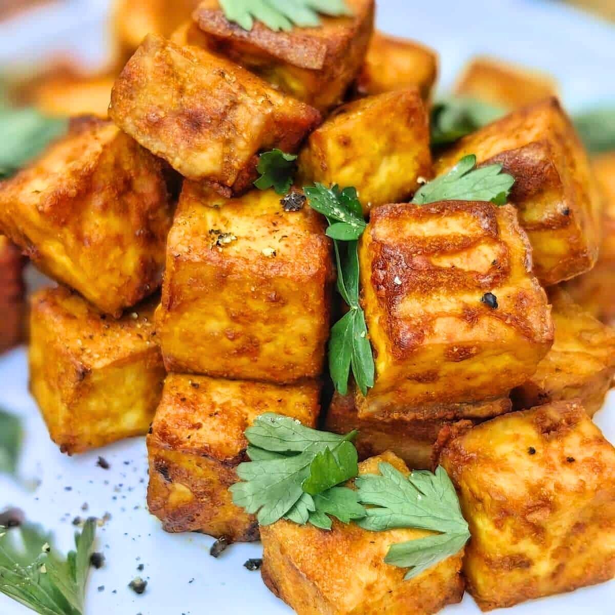 This looks like air-fried tofu. It has a golden-brown crust and is sprinkled with parsley.