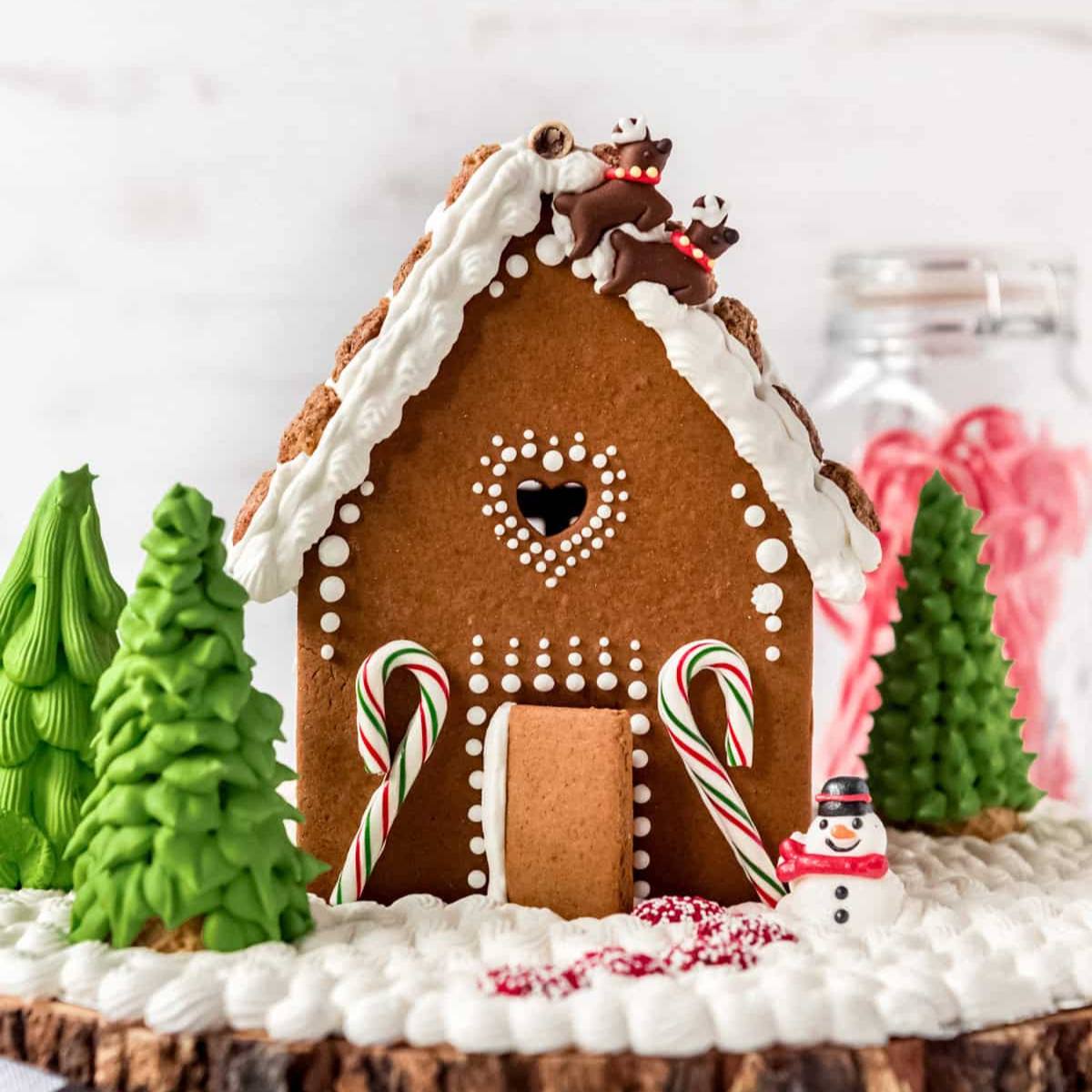 A whimsical gingerbread house decorated with reindeer figurines, candy canes, and a snowman.