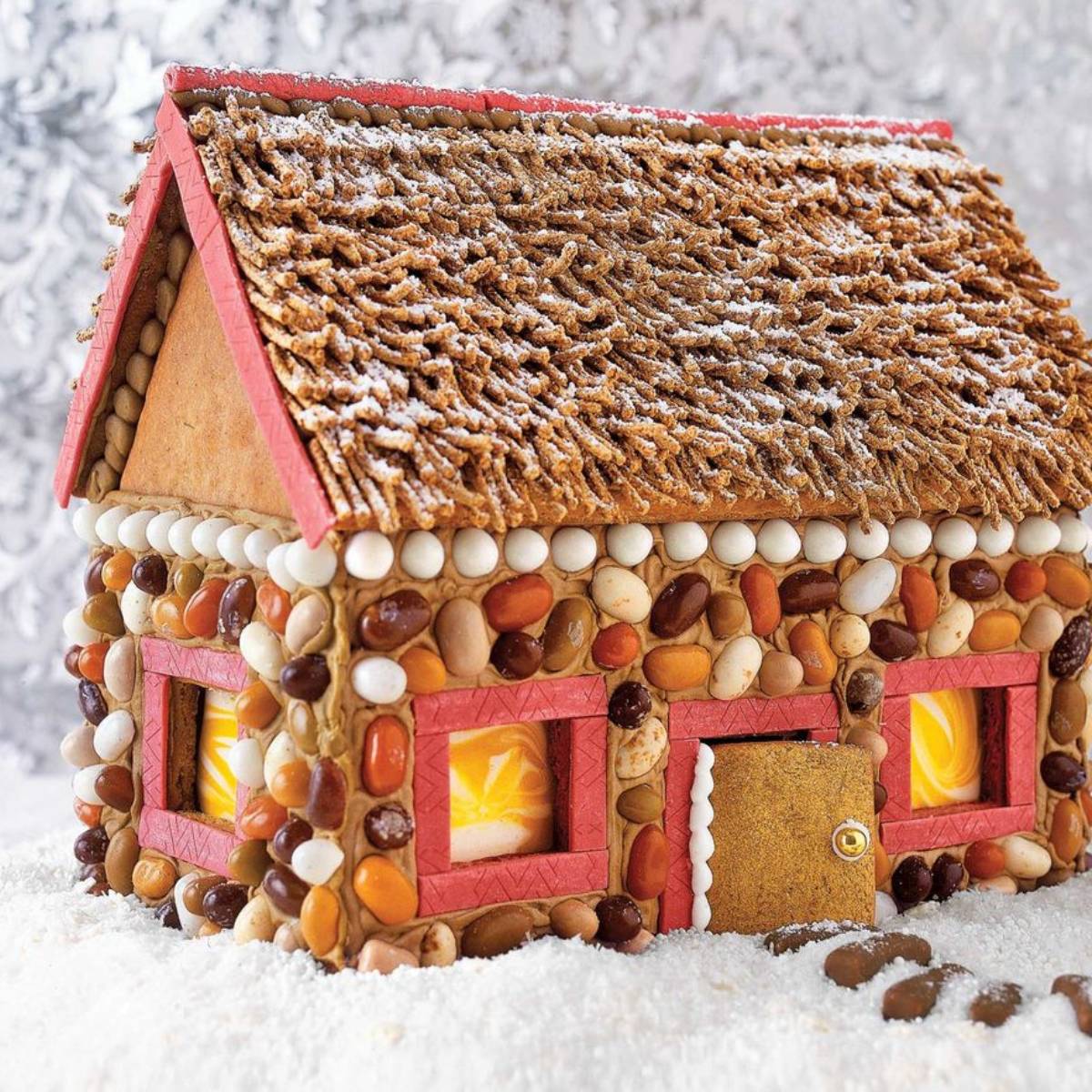 An elaborately decorated gingerbread house with a candy pebble roof and windows.