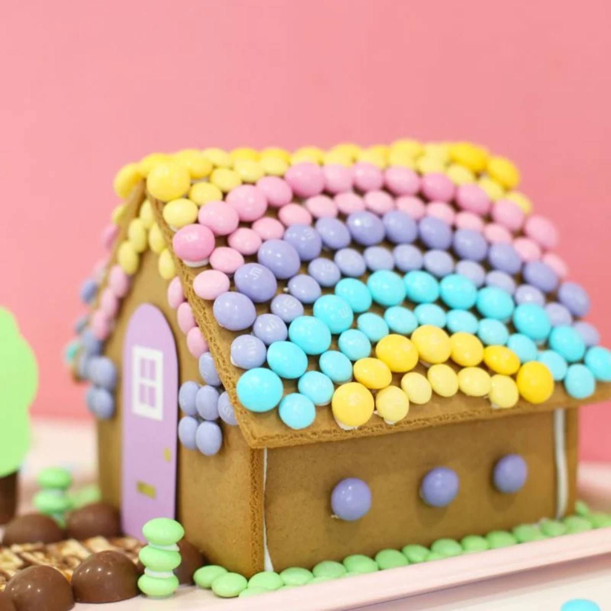 A pastel gingerbread house with a roof made entirely of colorful candies.