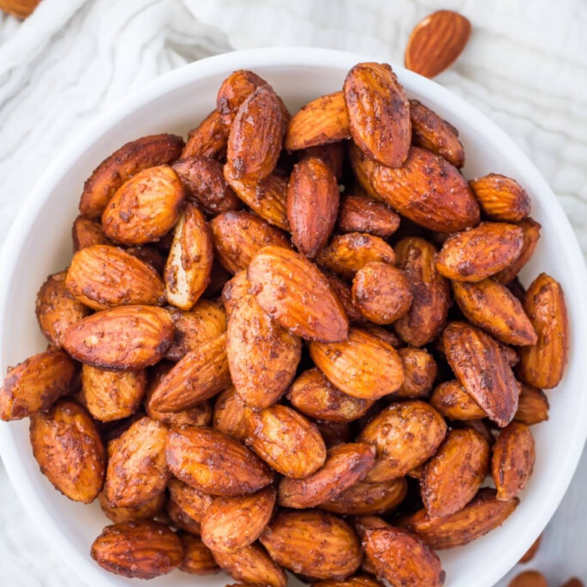 A bowl of air fried almonds. The almonds are golden brown and look crispy and seasoned with spices.