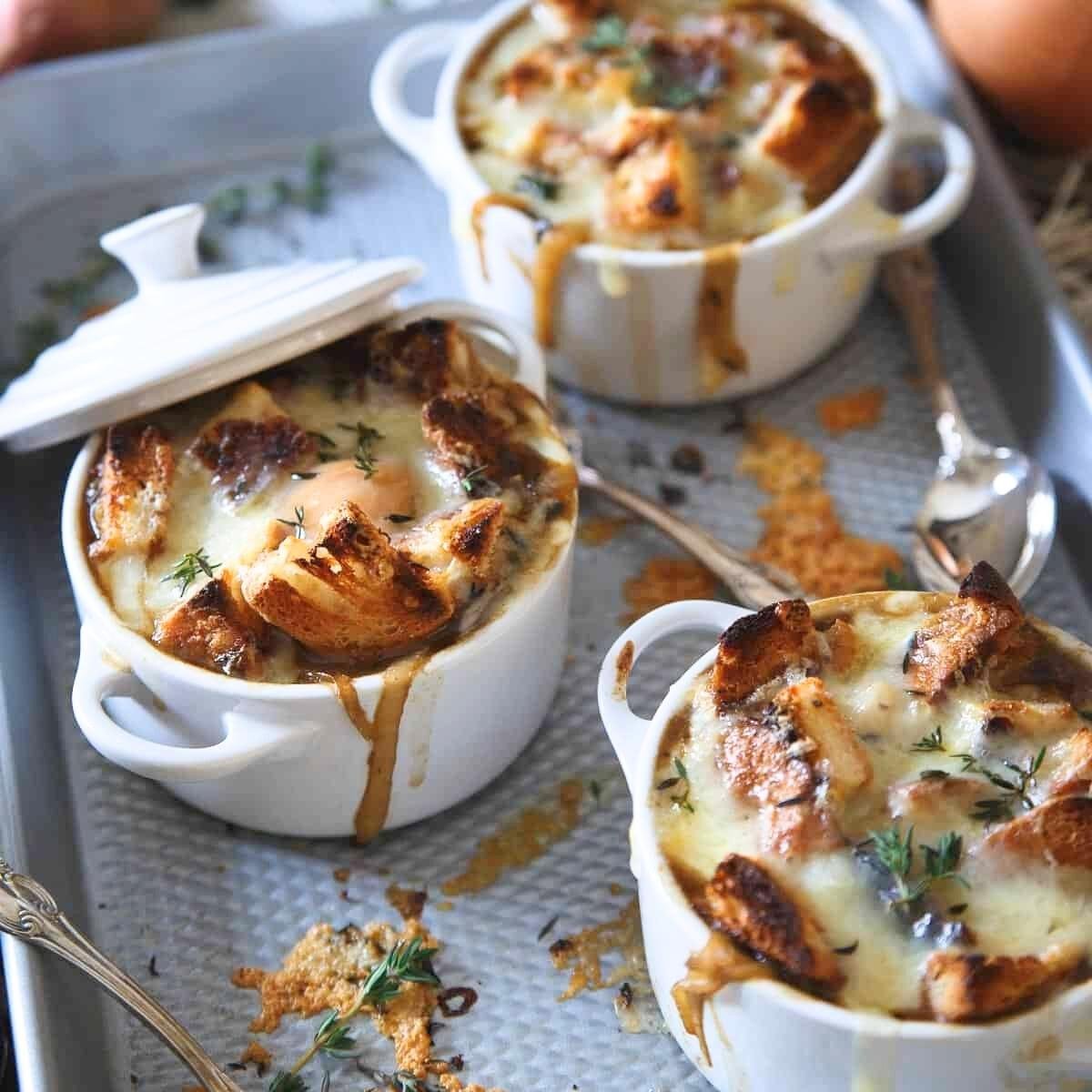 Three bowls of French Onion Soup, each topped with a golden-brown crouton, melted cheese, and a sprig of thyme.