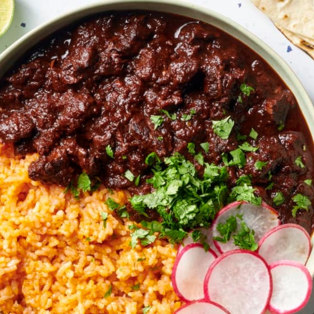 A bowl of rich and savory Chile Colorado, a Mexican stew featuring tender beef simmered in a deep red chili sauce. The stew is served over a bed of fluffy white rice and garnished with fresh cilantro and radish slices.