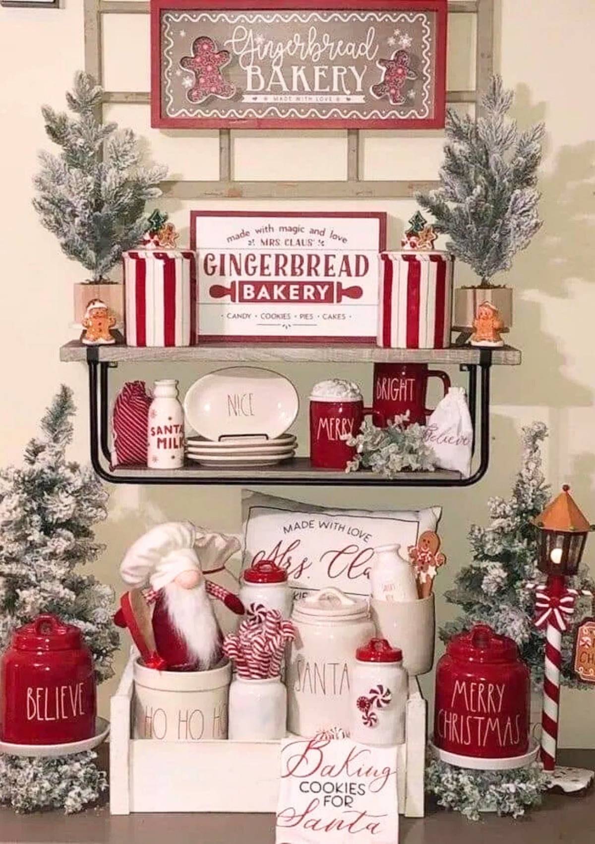 A festive Christmas display with a "Gingerbread Bakery" sign, red and white striped pots, Christmas trees, and various holiday decorations.