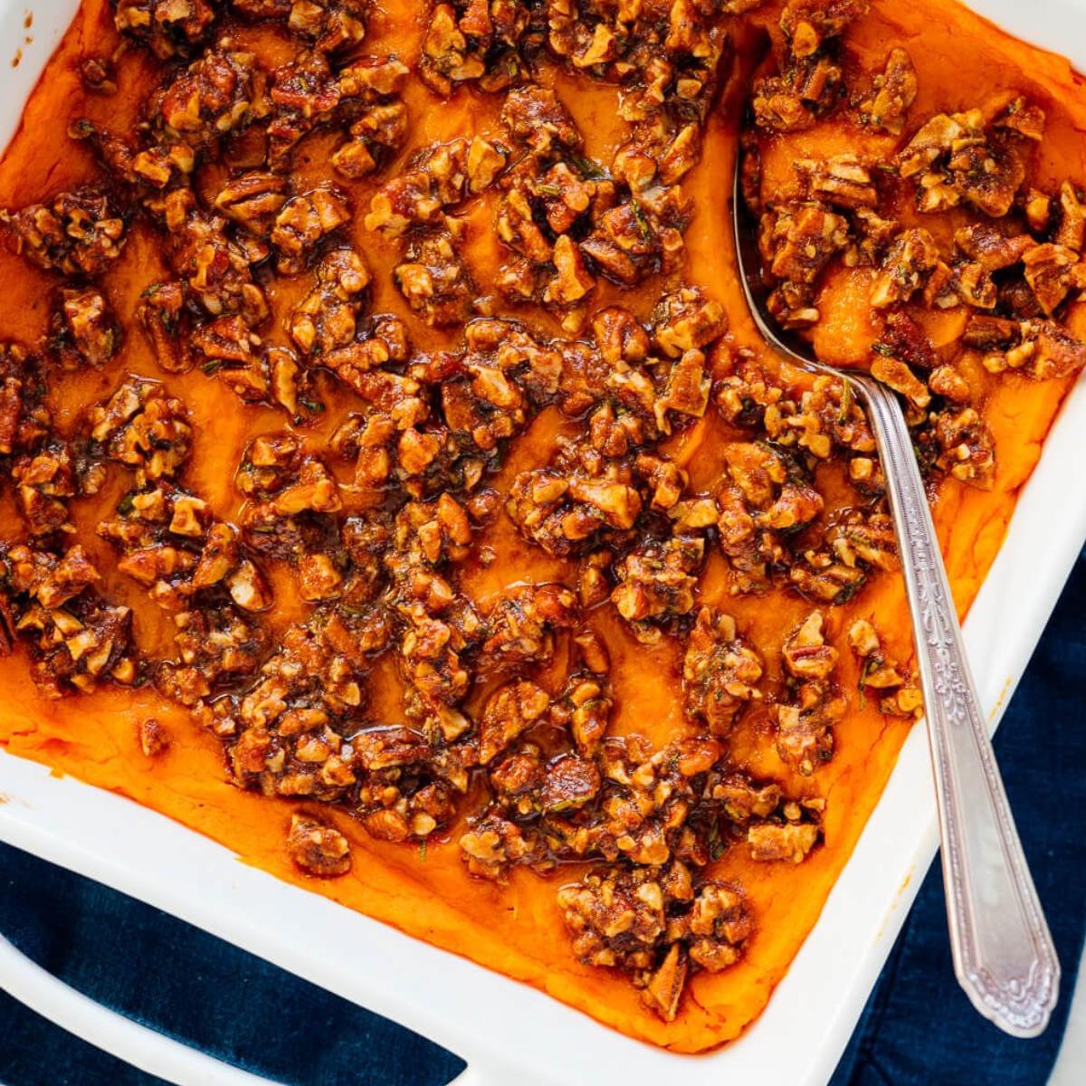 A dish of creamy mashed sweet potatoes topped with a crunchy pecan streusel.