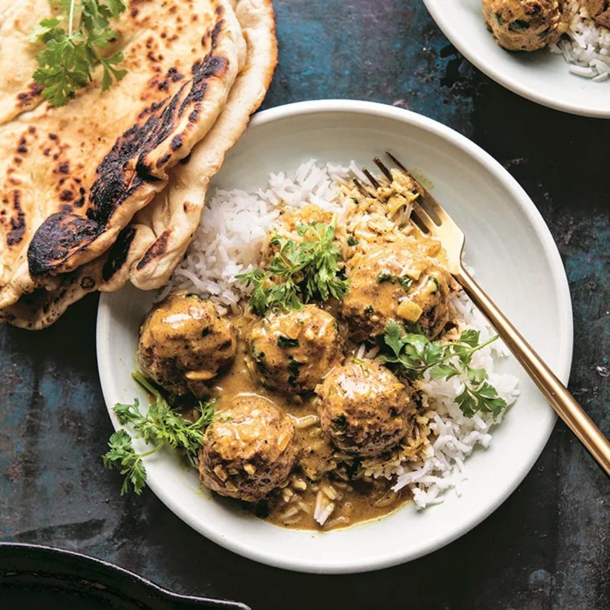 A bowl of fragrant chicken curry with fluffy rice, served alongside warm naan bread.