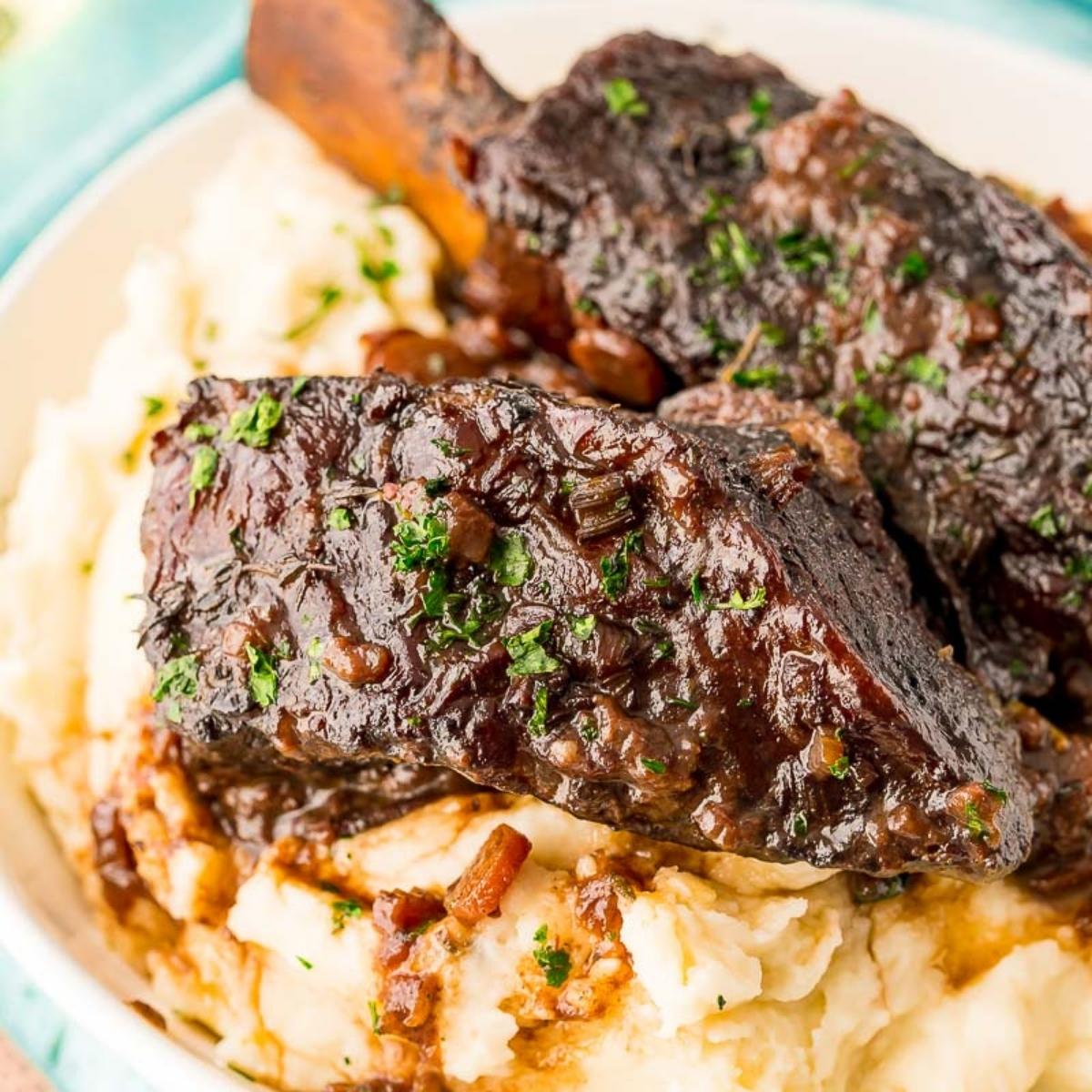 A close-up of tender, fall-off-the-bone short ribs smothered in a rich, dark gravy.