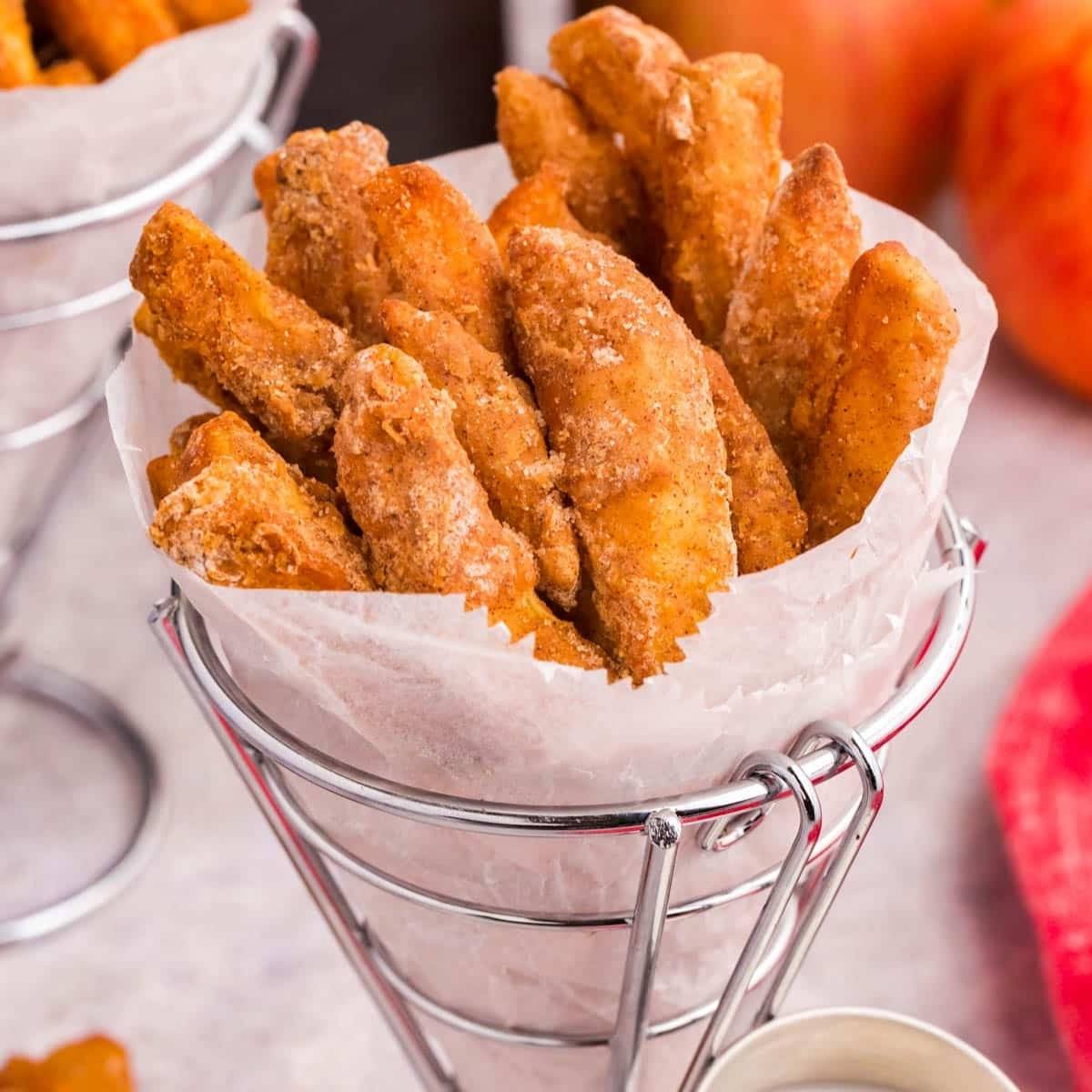 A basket of crispy, golden-brown apple fries. The fries are coated in cinnamon sugar and look delicious.