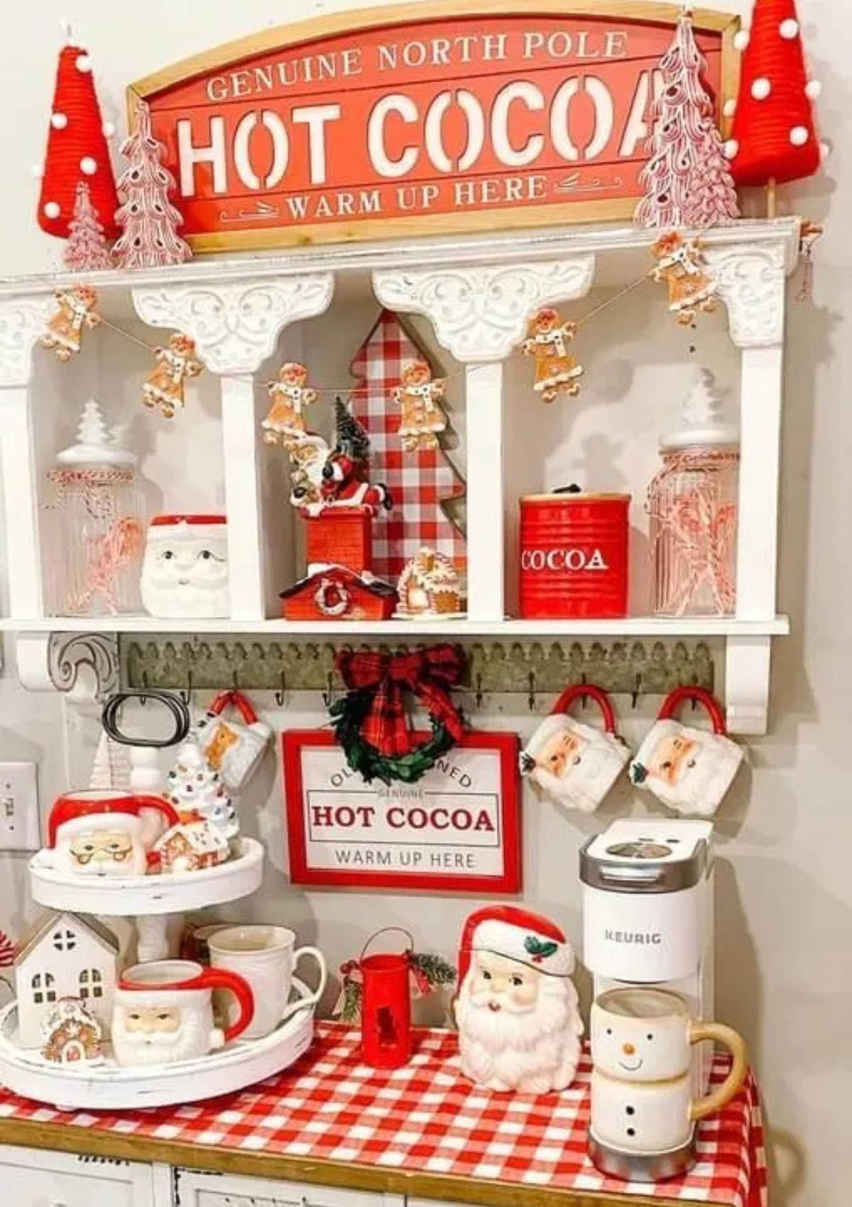 A festive hot cocoa bar with a variety of mugs, candy canes, and other decorations. There is also a Keurig coffee maker and a sign that says "Genuine North Pole Hot Cocoa".