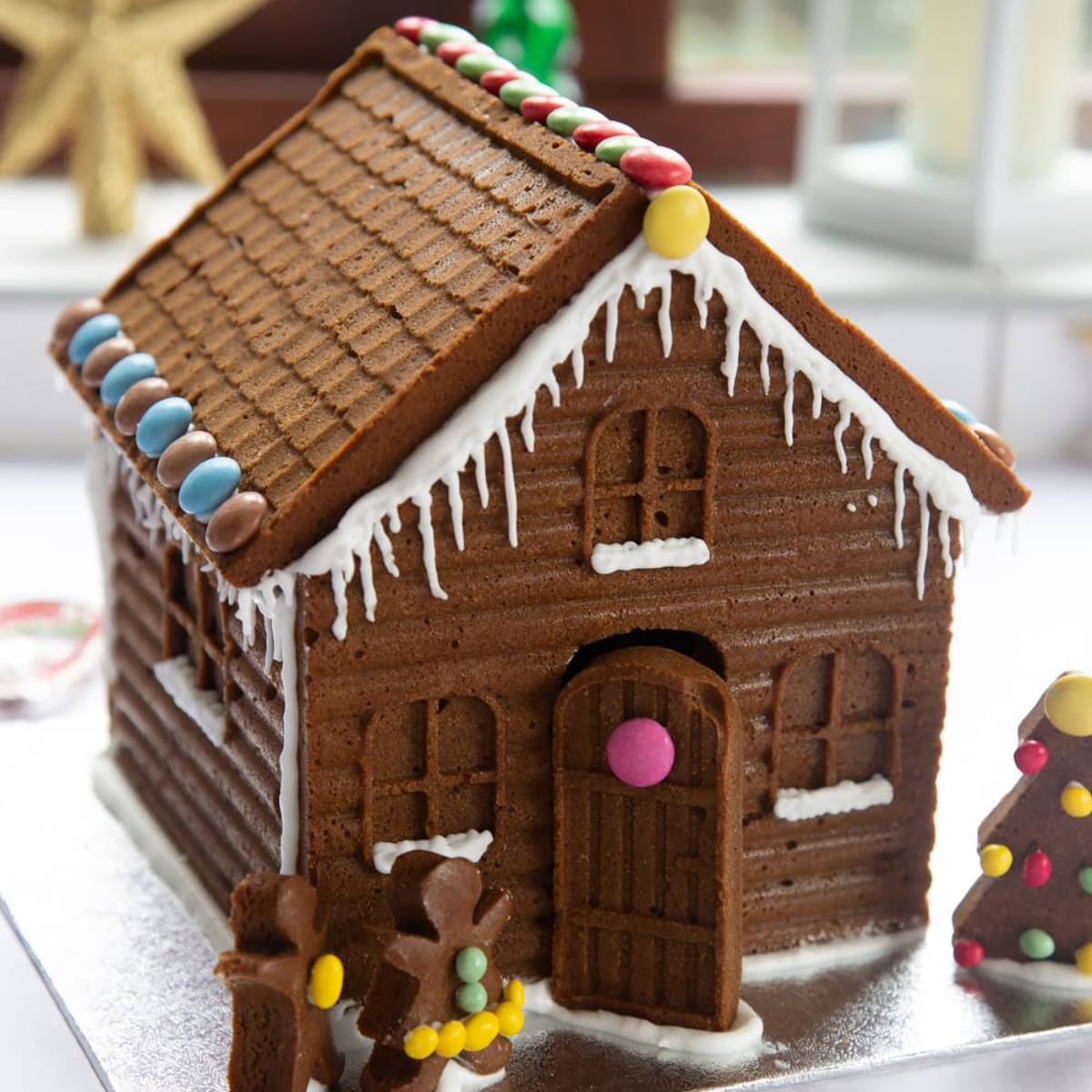 A festive gingerbread house with a round candy door, decorated with icing and colorful candies.