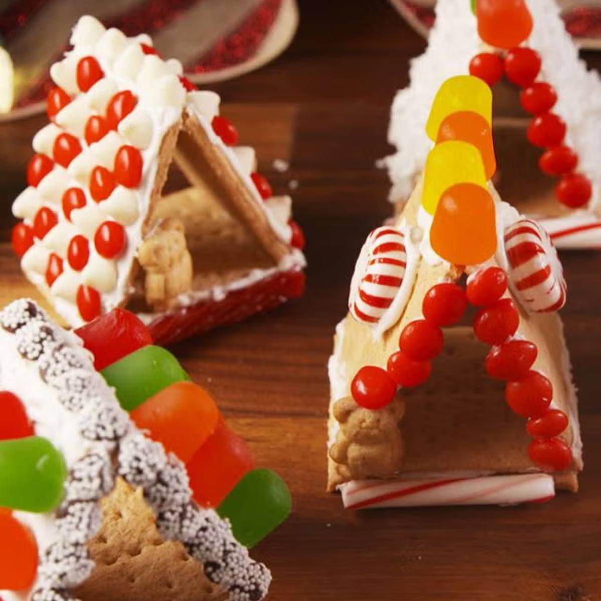 A group of creatively decorated gingerbread houses with various candy toppings, including gumdrops, candy canes, and sprinkles.